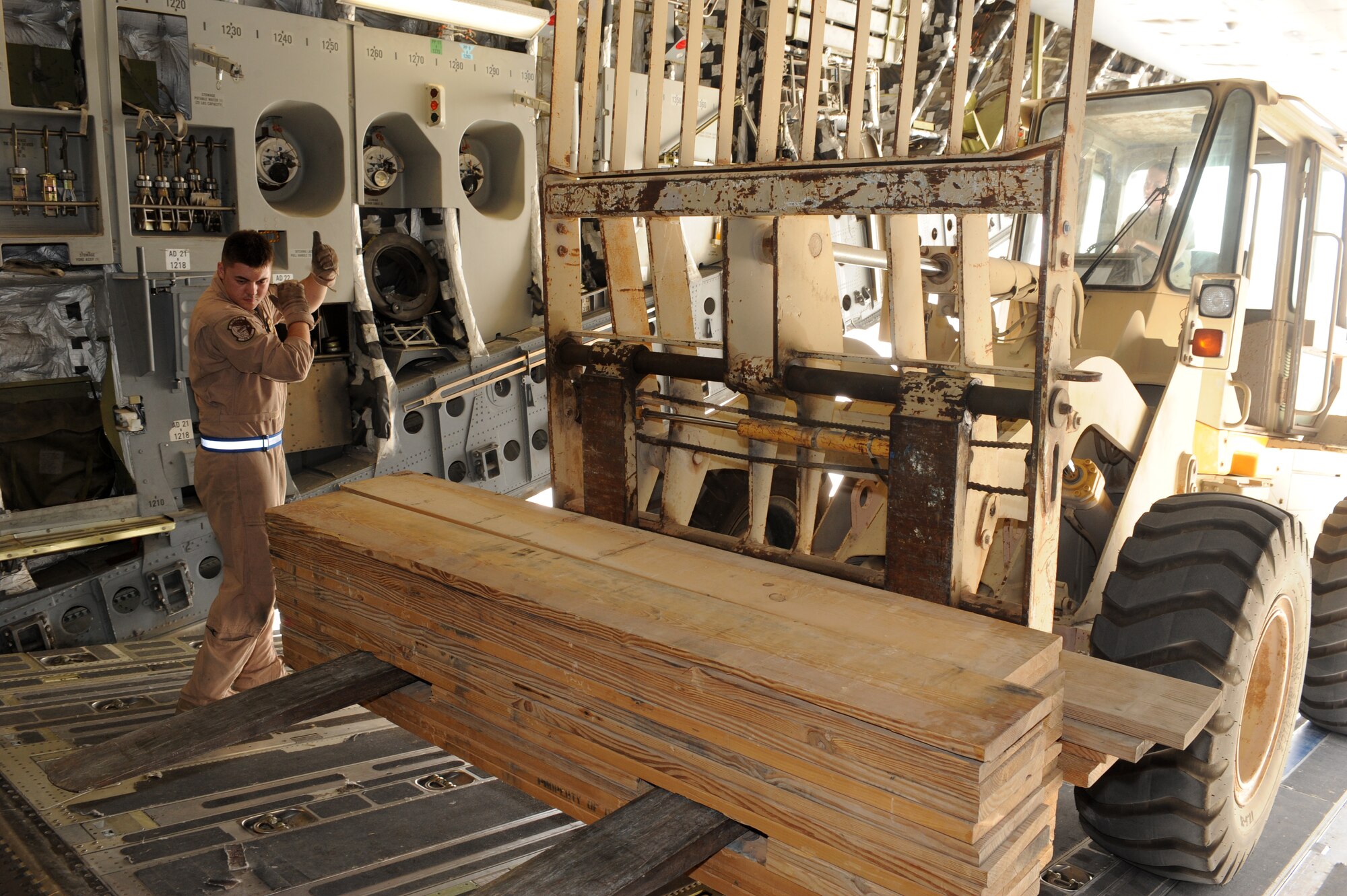 SOUTHWEST ASIA -Airman 1st Class Brad Benny, C-17 loadmaster, directs movement of a forklift driven by Staff Sgt. Heather Stephens, 380th Expeditionary Logistics Readiness Squadron, Air Terminal Operations Center journeyman, on a C-17 aircraft Aug 14. Airman Benny is from Dover AFB, Del., and hails from Grain Valley, Mo. Sergeant Stephens is deployed from Andrews AFB, Md., and hails from Mt. Vernon, Ohio. (U.S. Air Force photo/Tech. Sgt. Charles Larkin Sr)
