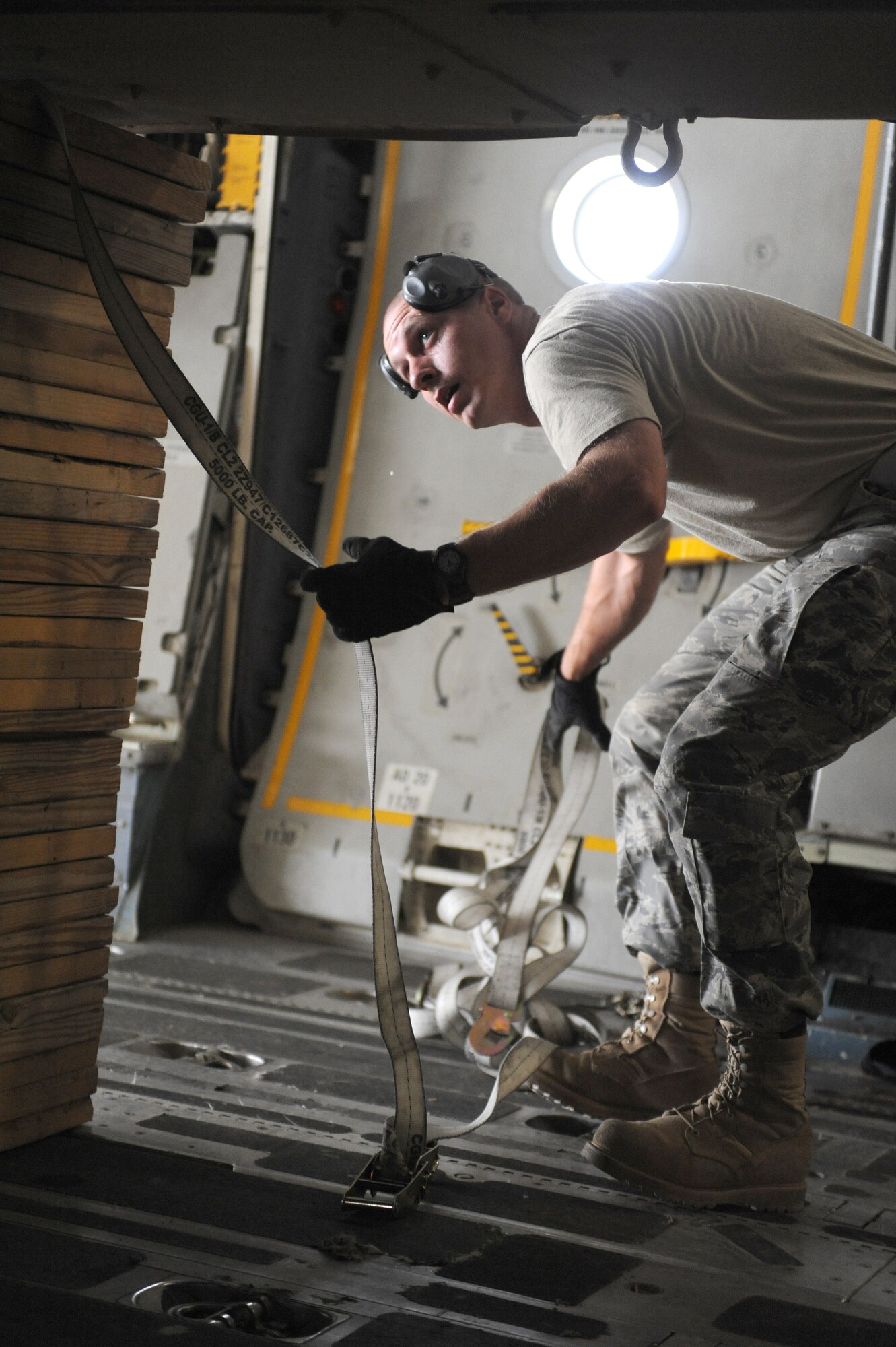 SOUTHWEST ASIA -Tech. Sgt. Andrew McMahon, 380th Expeditionary Logistics Readiness Squadron, Air Terminal Operations Center Craftsman, removes a tie down strap from cargo on a C-17 aircraft Aug 14. Sergeant McMahon is deployed from Andrews AFB, Md., and hails from Van Wert, Ohio. (U.S. Air Force photo/Tech. Sgt. Charles Larkin Sr)