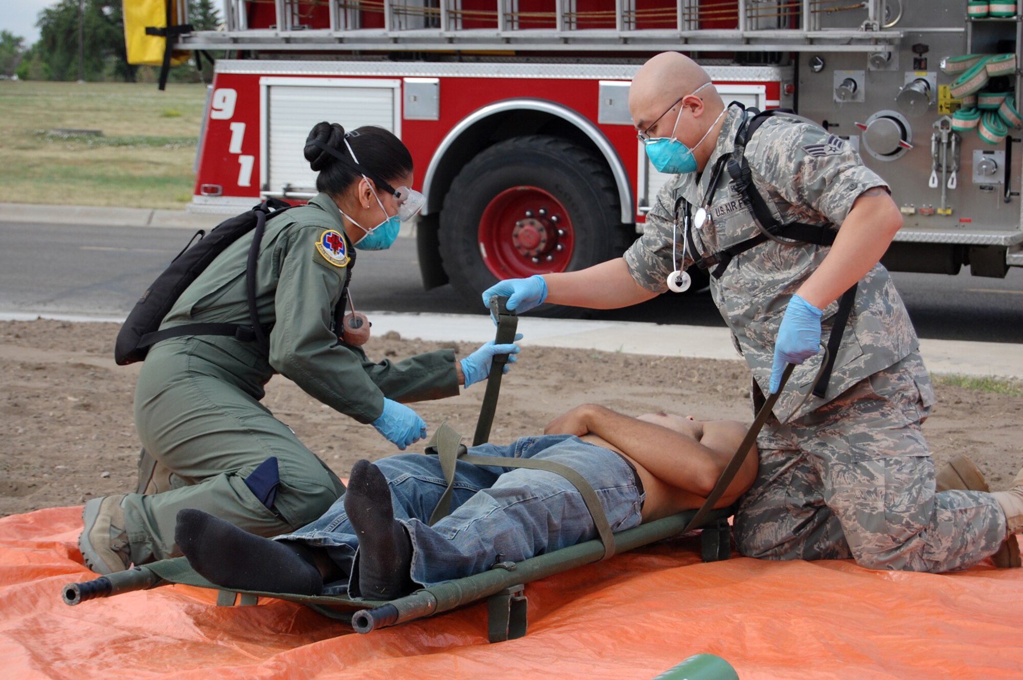 Senior Airman Malaya Movido joins Senior Airman Kenvin Keophakdy in securing a patient onto a gurney during a mass casualty exercise at Malmstrom Air Force Base July 17. The two Airmen from the 341st Medical Operations Squadron were participants in the exercise, which was a culmination of this week’s Medical Emergency Response Capability Assessment and Training. The MERCAT evaluated Malmstrom medics on how well they provide care for patients, especially during emergencies. More than 100 volunteers with simulated injuries requiring immediate care were treated inside and outside of the clinic by 341st Medical Group medics. (U.S. Air Force photo/Staff Sgt. Marcus McDonald)