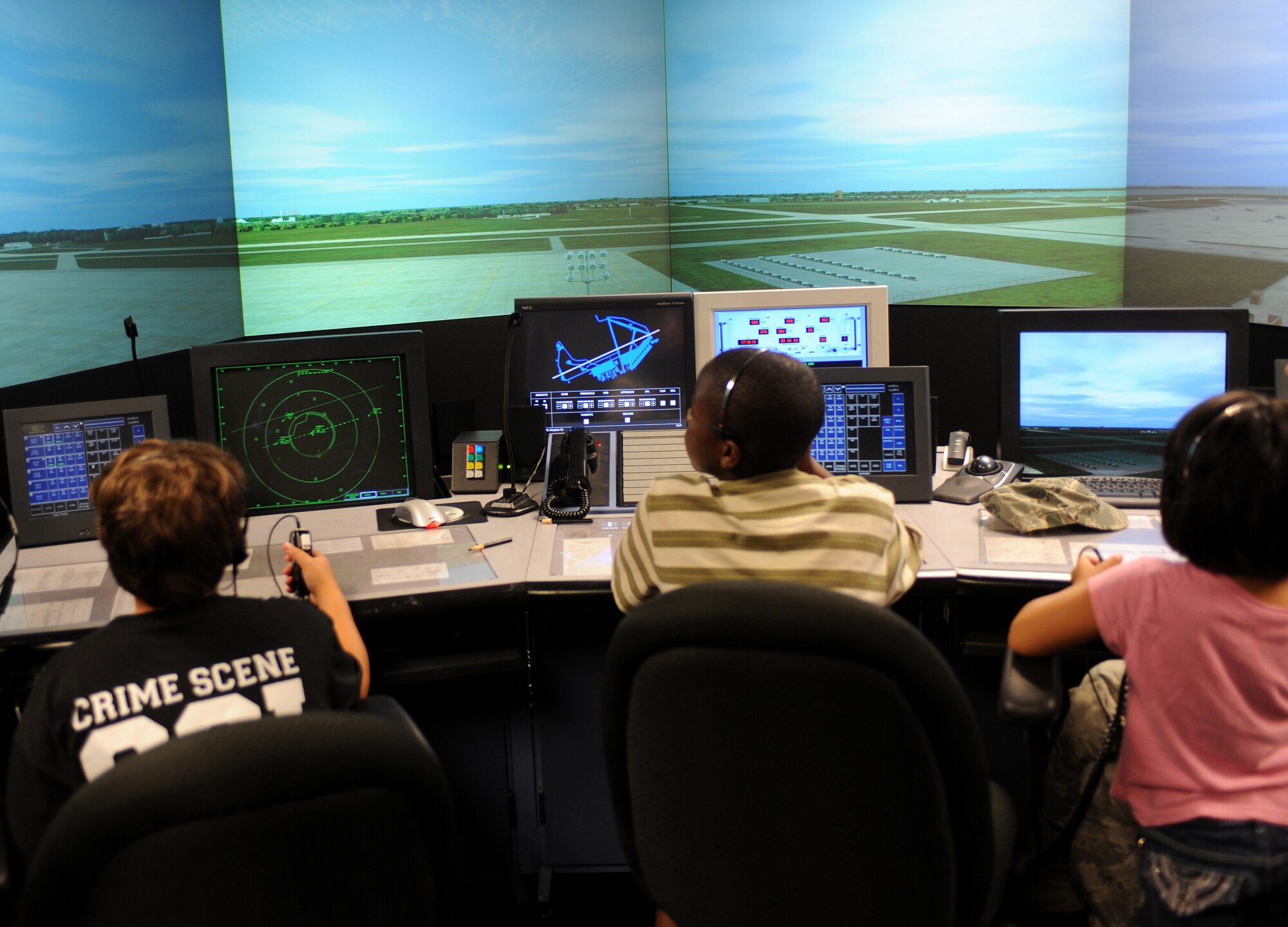 LANGLEY AIR FORCE BASE, Va. -- Nicholas, age 12, Bryant, age 15, and Meesha, age five, practice directing air traffic during a tour of the Air Traffic Control simulator Aug. 6. The children were part of a group from Portsmouth Naval Hospital Pediatrics Oncology that were invited to base for a special tour of the F-22 Raptor, the Air Traffic Control Tower, and an F-22 demonstration flight. (U.S. Air Force photo/Amn Rebecca Montez)