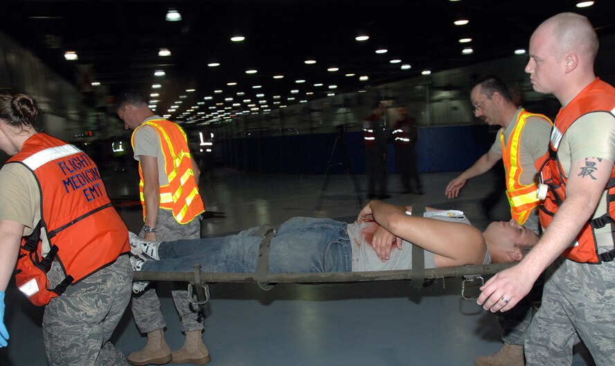 OFFUTT AIR FORCE BASE, Neb. - Emergency medical personnel carry simulated victims on stretchers during the Major Accident Response Exercise Aug. 15 at the Offutt Field House. The MARE was a simulated plane crash excercise with volunteer victims from all over the Metro area participating with simulated injuries. U.S. Air Force photo by Kendra Williams