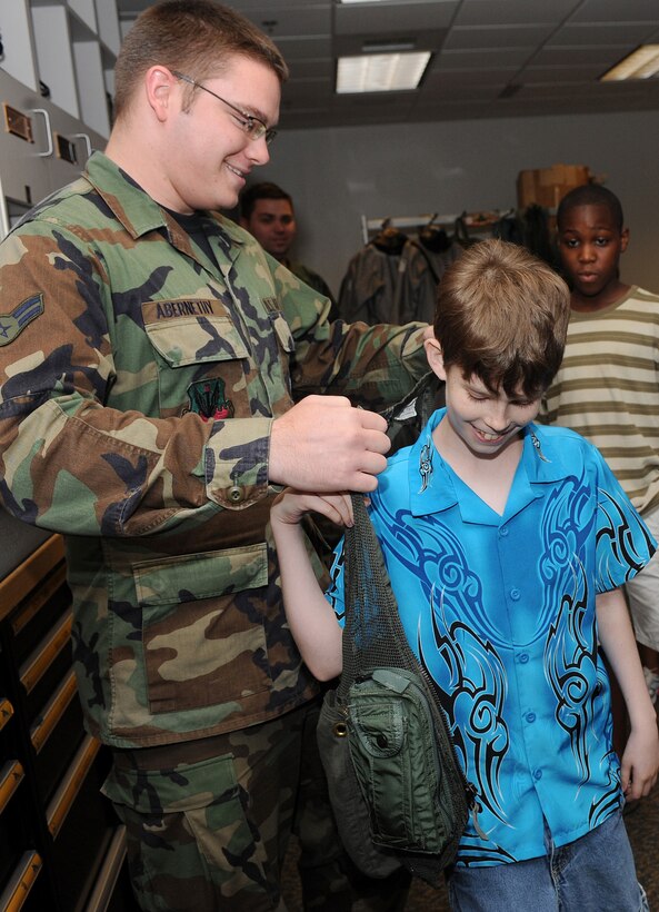 LANGLEY AIR FORCE BASE, Va. – Airman 1st Class Charles Abernathy, 1st Operations Support Squadron aircrew flight equipment apprentice, helps Joseph, age 13, try on a survival vest during a tour of the 27th Fighter Squadron "Life Support" section Aug. 6. Joseph was part of a group from Portsmouth Naval Hospital Pediatrics Oncology that were invited to base for a special tour of the F-22 Raptor, the Air Traffic Control Tower, and an F-22 demonstration flight. (U.S. Air Force photo/Amn Rebecca Montez)