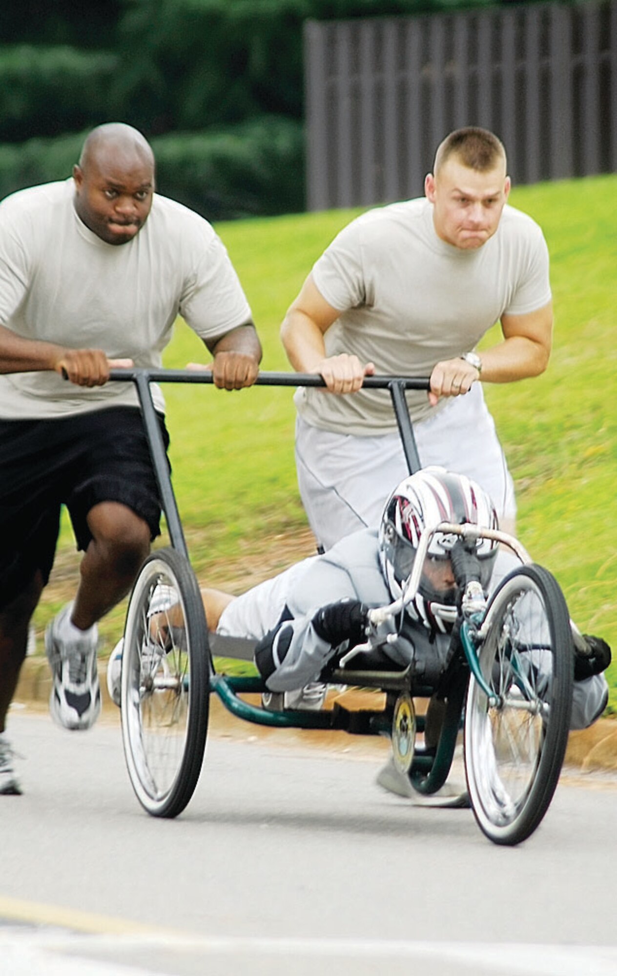 Staff Sgt. Jason Thomas and 2nd Lt. Justin Schultz, members of the 43rd Civil Engineer Squadron, push 1st Lt. Esamu Cooper down Reilly Street during the Pope Box Derby Aug. 6. (U.S. Photo by Senior Airman Mindy Bloem)
