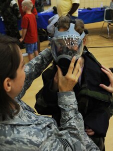 LANGLEY AIR FORCE BASE, Va. -- Staff Sgt. Jennifer Foster,1st Fighter Wing Public Affairs broadcaster, helps Dakota Autrey fit into a chemical warfare suits during Operation Hero here Aug. 14. Operation Hero shows children some of the ways their parents prepare for deployment by letting them participate in various hands on activities. (U.S. Air Force photo/Senior Airman Scott Aldridge)