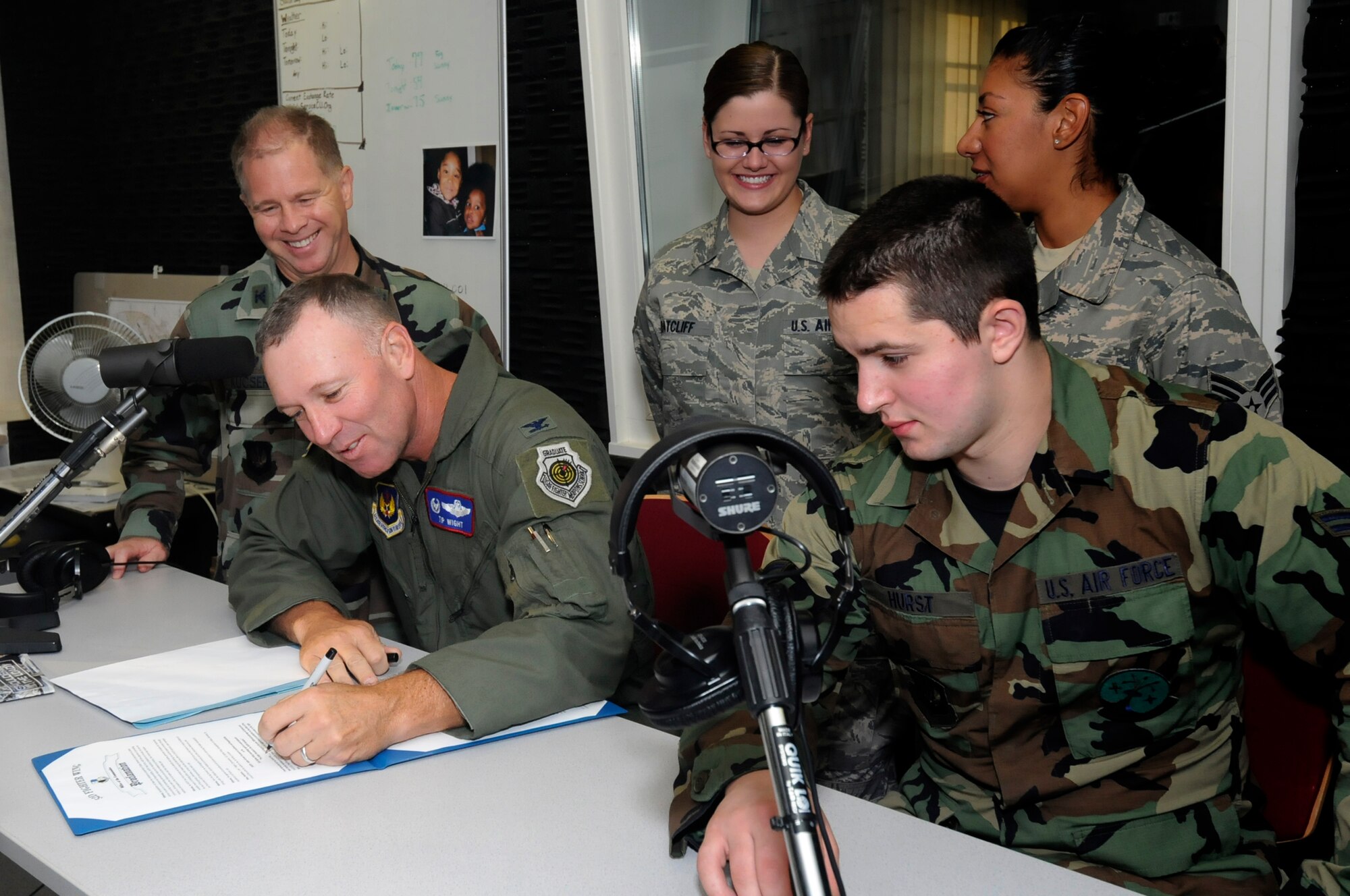 Col. Tip Wight, 52nd Fighter Wing commander and Col. Michael Kucsera, 52nd Dental Squadron commander, sign a proclamation establishing the Saber Airmen Focused on Excellence and Responsibility Task Force into effect during the Armed Forces Network Commander’s Hour radio spot Aug. 14.   SAFER Task Force members promoting the group included Airman First Class Brittany Ratcliff, Senior Airman Kimberly Luera and designated spokesperson Airman First Class James Hurst, who discussed the purpose of the task force on the radio.  (U.S. Air Force photo/Master Sgt. Bill Gomez)