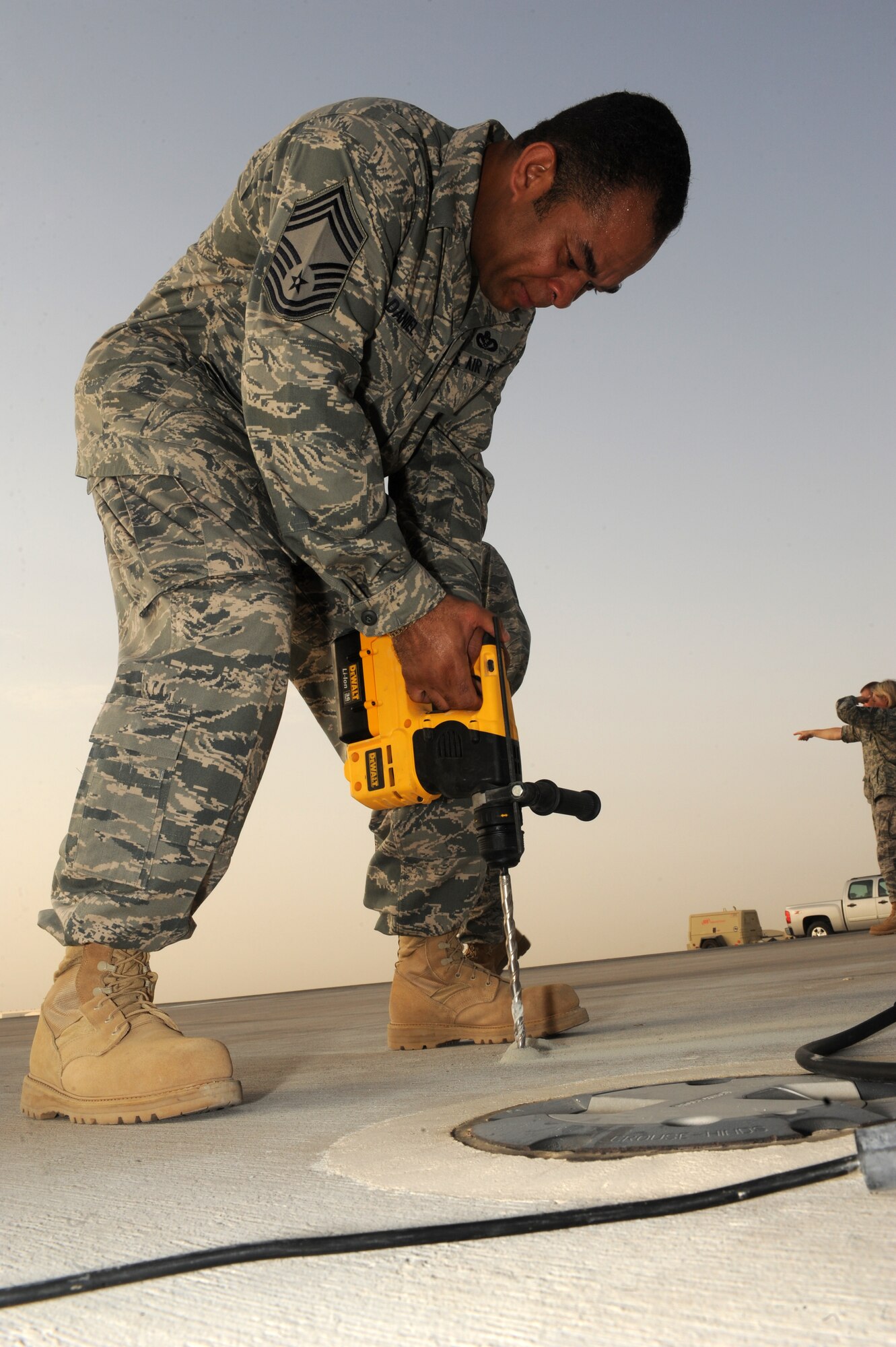 SOUTHWEST ASIA -Chief Master Sgt. David Daniel, 380th Expeditionary Civil Engineer Squadron, assists his Airmen with drilling holes in the concrete to install runway lights Aug. 15. Chief Daniel is deployed from Aviano AB, Italy, and hails from Texas. (U.S. Air Force photo/Tech. Sgt. Charles Larkin Sr)