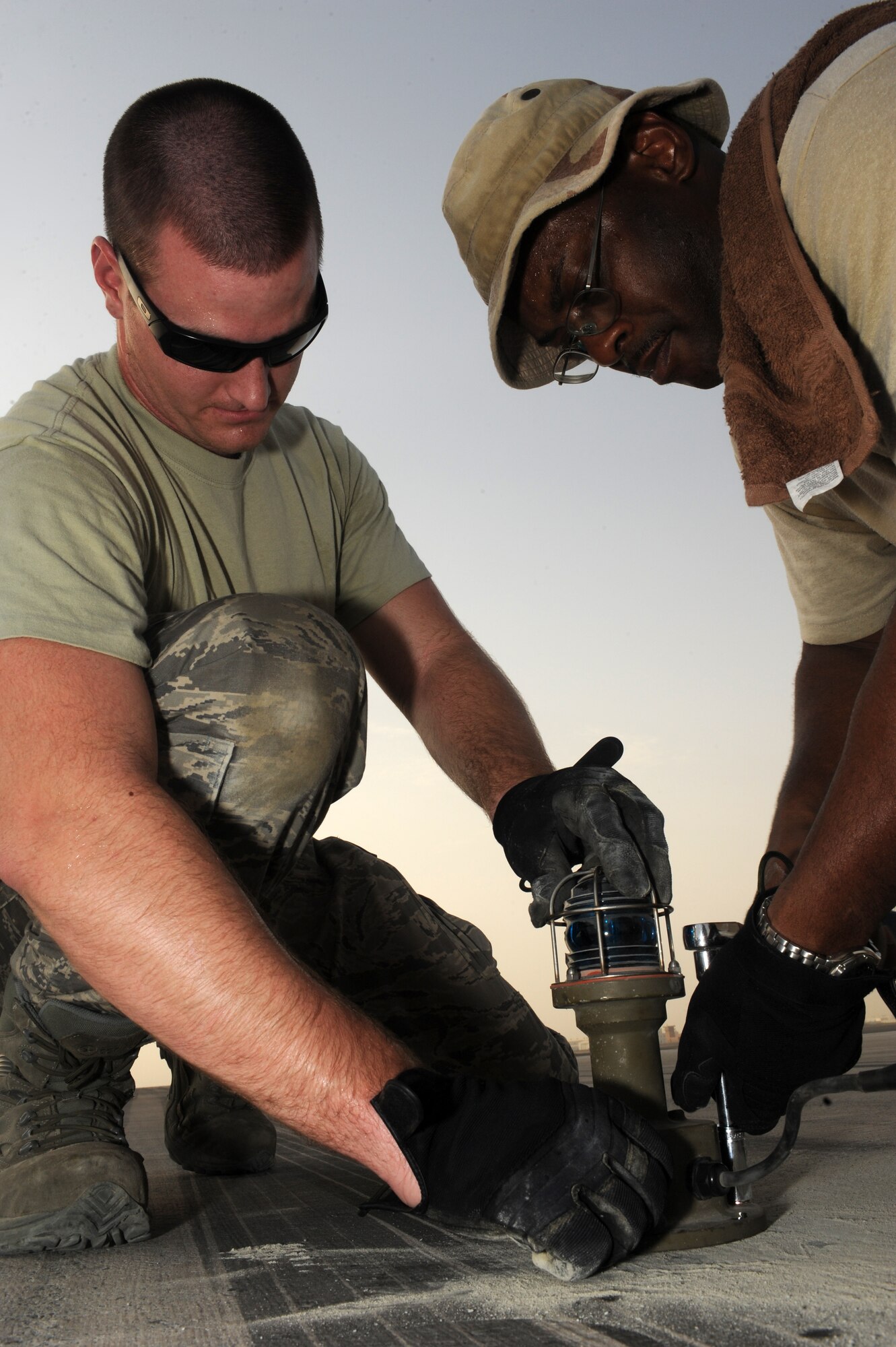 SOUTHWEST ASIA -Senior Airman Stephen Huff, 380th Expeditionary Civil Engineer Squadron, and Master Sgt. Darryl Harris, 380th ECES, install a runway light Aug. 15, 2009. Airman Huff is deployed from Travis Air Force Base, Calif., and hails from Anchorage, Alaska. Sergeant Harris is deployed from Spangdahlem Air Base, Germany, and hails from Detroit. (U.S. Air Force photo/Tech. Sgt. Charles Larkin Sr)