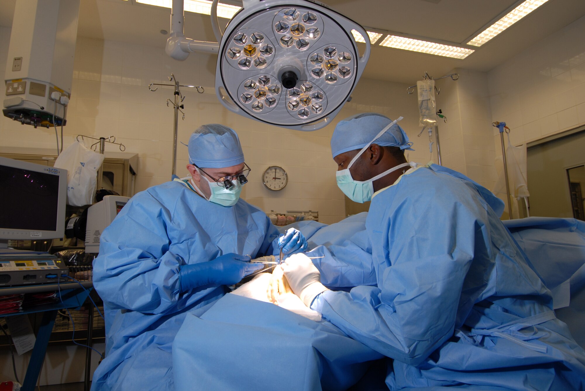 Leftt, Maj. Todd Grebner, 379th Expeditionary Medical Group staff orthopedic surgeon, removes a cyst from a patient's wrist with the aid of Airman 1st Class Frederick Fortenberry, 379 EMDG surgical technician. Major Grebner hails from Metamora, Ill. and is deployed from Sheppard Air Force Base, Texas. Airman Fortenberry is a native of Sandy Hook, Miss. and is deployed from Keesler Air Force Base, Miss. Both are deployed in support of Operations Iraqi and Enduring Freedom. (U.S. Air Force Photo/Tech. Sgt. Jason W. Edwards)