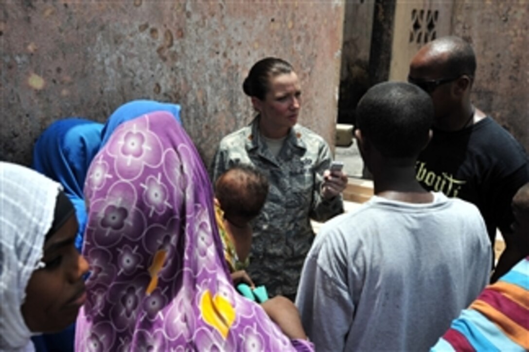 U.S. Air Force Maj. Lisa Ahaesy, a public affairs officer with Combined Joint Task Force - Horn of Africa, interviews a family in front of their burned home in the Boulas commune of Djibouti City on Aug. 12, 2009.  Their home is one of 21 buildings destroyed in a fire on Aug. 10, 2009.  U.S. soldiers from the 478th Civil Affairs Battalion and sailors from Maritime Civil Affairs Team 104 are delivering supplies and donated building materials to the fire victims.  