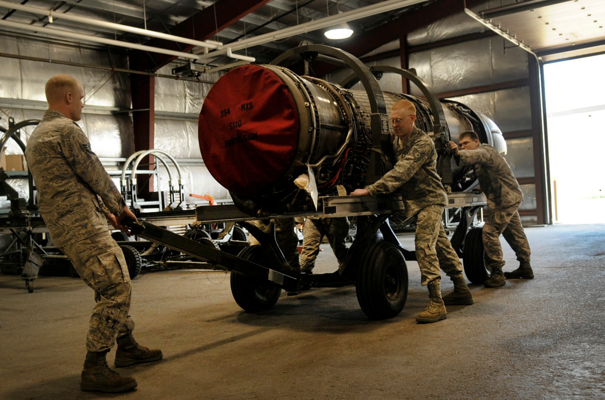 Airman 1st Class Kevin Henson guides the motor by pulling from the front while several Airmen maneuver the F-16 Fighting Falcon jet engine into the bay Aug. 12, 2009, Eielson Air Force Base, Alaska. The engine will be serviced for routine maintenance. The Airmen are with the 354th Maintenance Squadron. (U.S. Air Force photo/Airman 1st Class Laura Goodgame)