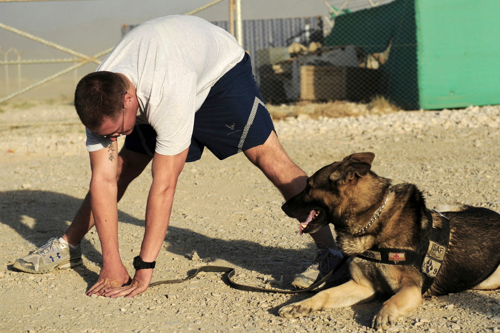 Staff Sgt. Justin Kitts stretches with his German shepherd, Mayo, Aug. 9 at Bagram Airfield, Afghanistan. Sergeant Kitts, an eight-year Air Force veteran, is a dog handler with the 455th Expeditionary Security Forces Squadron. He is deployed from Luke Air Force Base, Ariz. He and his dog patrol the base and inspect mail, luggage, and vehicles for narcotics. (U.S. Air Force photo/Staff Sgt. J.G. Buzanowski) 
