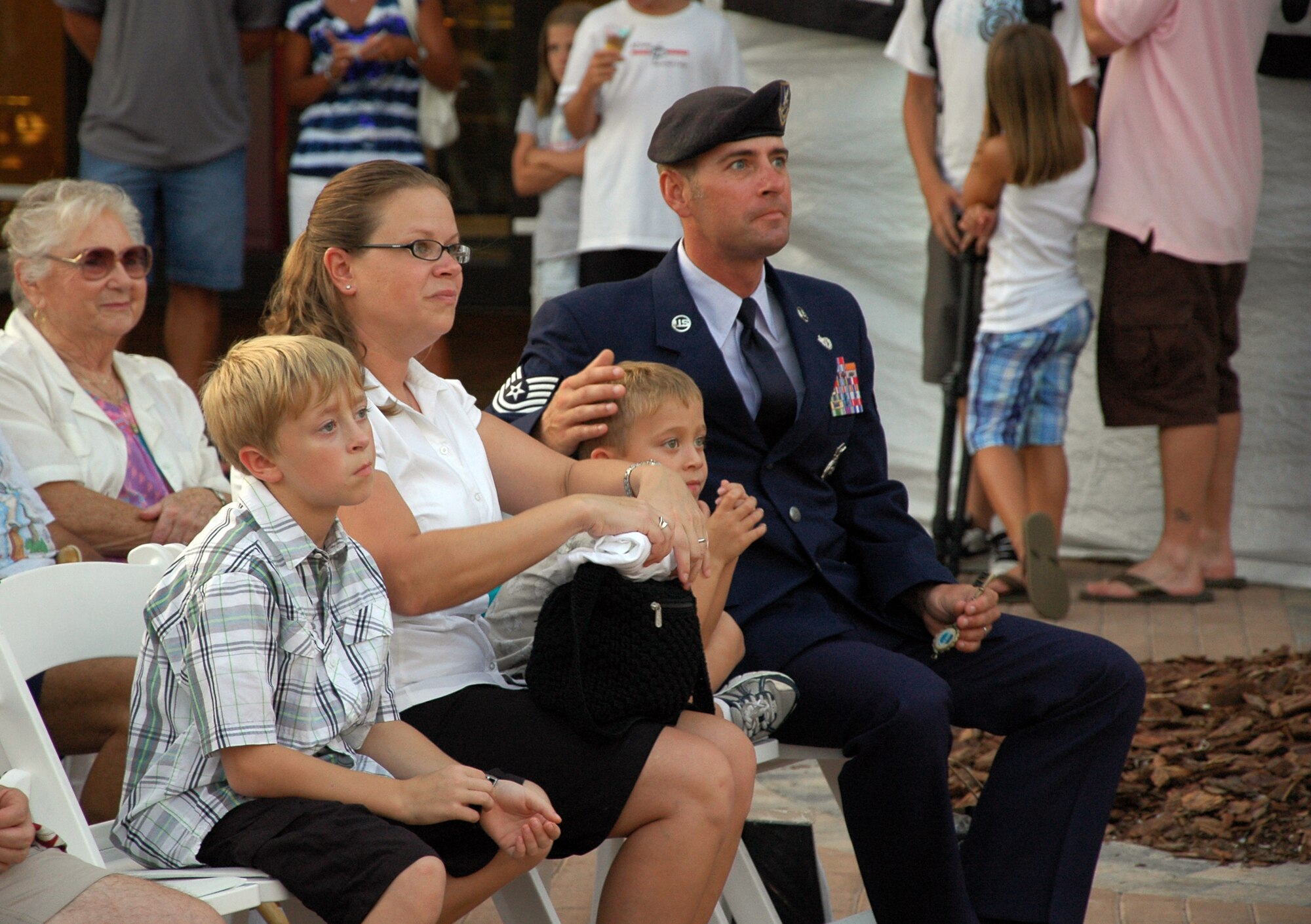 Tech. Sgt. Andy Shomake, non-commissioned officer in charge of the 96th Ground Combat Training Squadron's Military Working Dog Track, watches a patriotic show  with his family during the Red, White and Blue Celebration Aug. 13 at the Destin Harborwalk. The Pascagoula, Miss., native was the last Eglin servicemember to be recognized during the summer celebration. (U.S. Air Force Photo/Jasmine DeNamur)