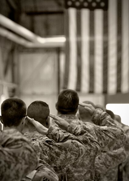 FAIRCHILD AIR FORCE BASE, Wash.–Army National Guard 81st brigade Soldiers salute a large draping flag at a hangar at Fairchild after returning from a year-long tour in Iraq Aug. 1. (U.S. Air Force photo / Staff Sgt. Anthony Enomoratto)  