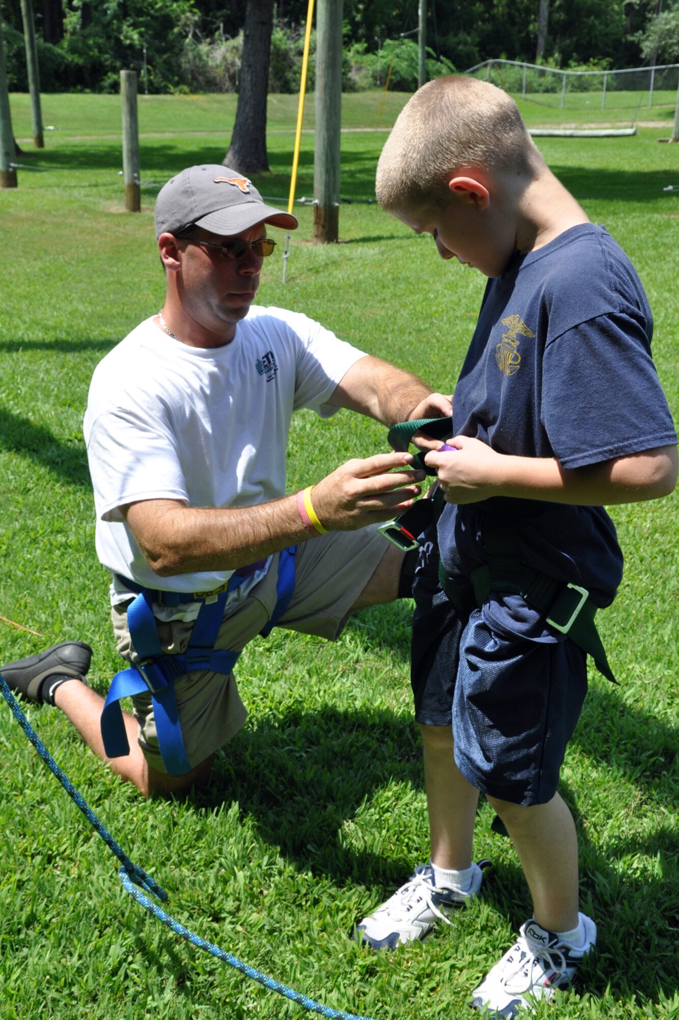 James Whitaker, activities therapy coordinator, East Texas Medical Center/Behavioral Health Center, assists Navy League Cadet Corps Recruit Christopher Leahy, TYLER JOINT FORCE Battalion, U.S. Naval Sea Cadets Corps, secure his harness before attempting an exercise at the rope course in Tyler, Texas, August 15, 2009. The cadets spent an entire day completing exercises which will enable them to work closer with and trust their fellow cadets and officers. These experiences will also benefit those cadets who decide to join the U.S. Military in the future. Objectives of the NLCC are: to give young people mental, moral and physical training, through the medium of naval and other instruction, with the object of developing principles of patriotism and good citizenship, and instilling in them a sense of duty, discipline, self-respect, and a respect for others. (Courtesy photo)  