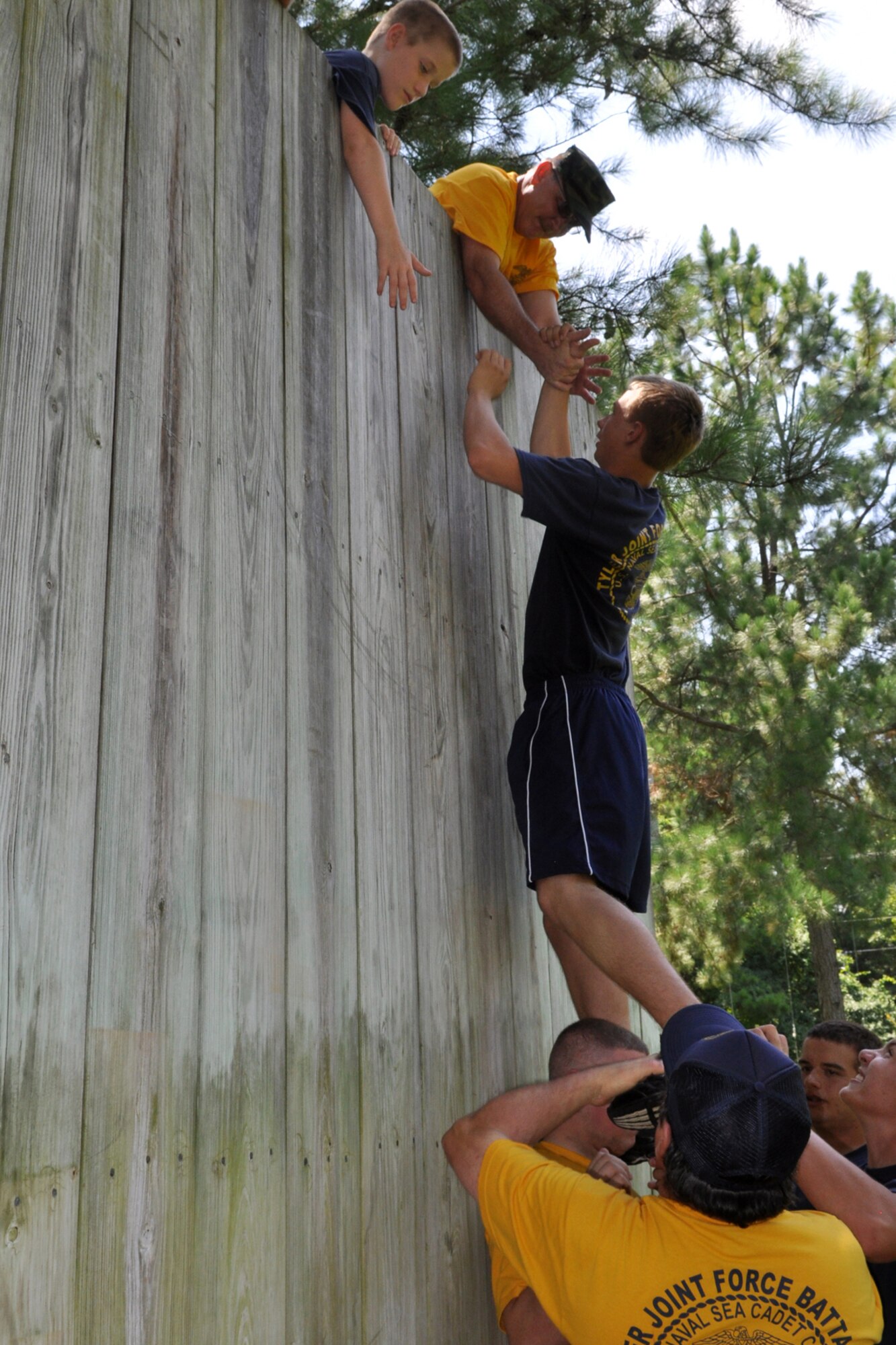 Members of the TYLER JOINT FORCE Battalion of the U.S. Naval Sea Cadets Corps based in Tyler, Texas, take part in an exercise which pits them against a 14-foot wall at the East Texas Medical Center’s Behavioral Health Center in Tyler, August 15, 2009. The exercise is used to help the cadets and officers realize the benefits of depending on a support system to accomplish goals. Participants at the wall learned quickly that without a support system they were unable to do a thing. The cadets spent the entire summer day completing exercises which will enable them to work closer with and trust their fellow cadets and officers. This experience will also benefit those cadets who decide to join the U.S. Military in the future. (Courtesy photo)      