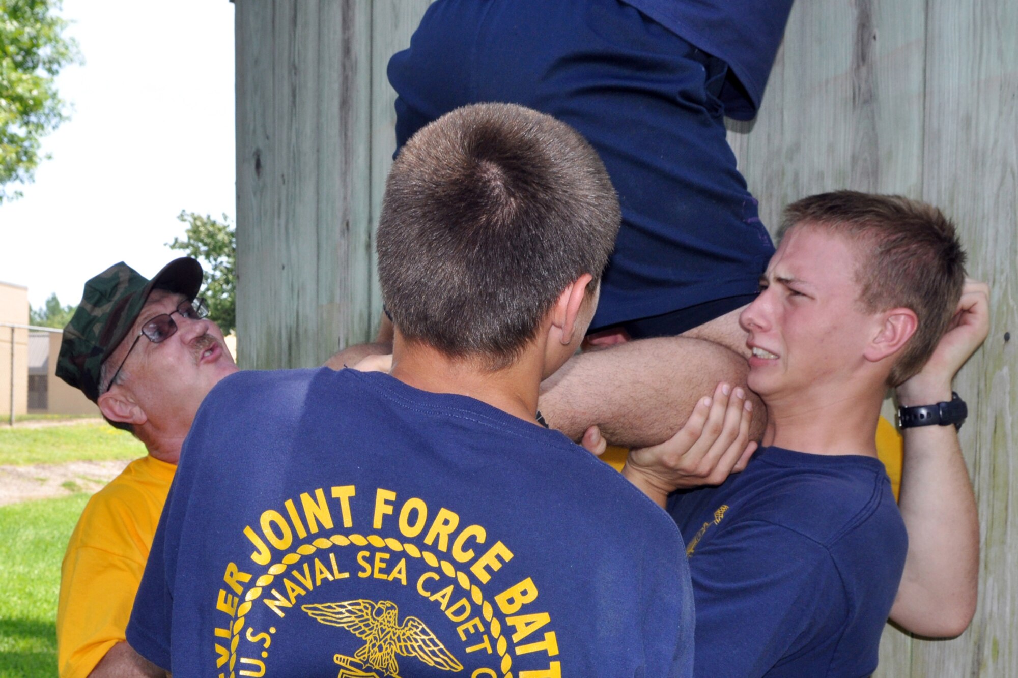Members of the TYLER JOINT FORCE Battalion of the U.S. Naval Sea Cadets Corps based in Tyler, Texas, take part in an exercise which pits them against a 14-foot wall at the East Texas Medical Center’s Behavioral Health Center in Tyler, August 15, 2009. The exercise is used to help the cadets and officers realize the benefits of depending on a support system to accomplish goals. Participants at the wall learned quickly that without a support system they were unable to do a thing. The cadets spent the entire summer day completing exercises which will enable them to work closer with and trust their fellow cadets and officers. This experience will also benefit those cadets who decide to join the U.S. Military in the future. (Courtesy photo)      