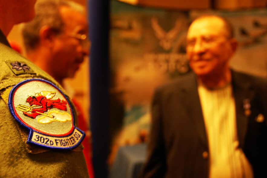 The 302nd Fighter Squadron Hellions, part of the 477th Fighter Group Elmendorf AFB, AK, can trace their unit history back to the courageous original Tuskegee Airmen.  During World War II, the 302nd FS was part of the 332nd Fighter Group, also known as "The Redtails," the famous all-Black unit that fought both American prejudice and Nazi militarism.  The 302nd was reactivated as part of the 477th FG in 2007 when the group became the Air Force Reserve Command's first F-22 Raptor unit.  Several of the original 302nd FS pilots , including retired Col. Charles McGee, and other original Tuskegee Airmen from the 477th Bombardment Group attended the 2007 reactivation ceremony, linking their incredible heroism and courage during WWII with the 477th FG's exciting future.  (Present in photo:  (Foreground) Hellion's patch worn by Lt. Col. Brian 'Pyro' Silkey, 302nd Fighter Group; (Background) Russell Davis, President, Tuskegee Airmen, Inc.; retired Lt. Col. James Warren, original Tuskegee Airmen and 477th Fighter Group Honorary Commander) (Air Force Photo / Maj. Cary McPartlin)