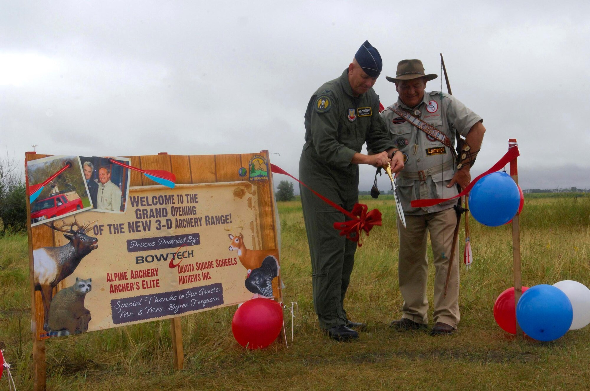 MINOT AIR FORCE BASE, N.D. -- The world’s greatest expedition shooter, Byron Ferguson of Hartselle, Alabama, and Col. Joel Westa, 5th Bomb Wing commander, cut the ceremonial ribbon marking the grand opening of the new 3-D archery range here, Aug. 15. Ferguson came to Minot to open the 3-D archery range hosted by outdoor recreation, talk about archery safety, and to demonstrate some of his trick shots with his long bow. (U.S.  Air Force photo by Airman 1st Class Jesse Lopez)