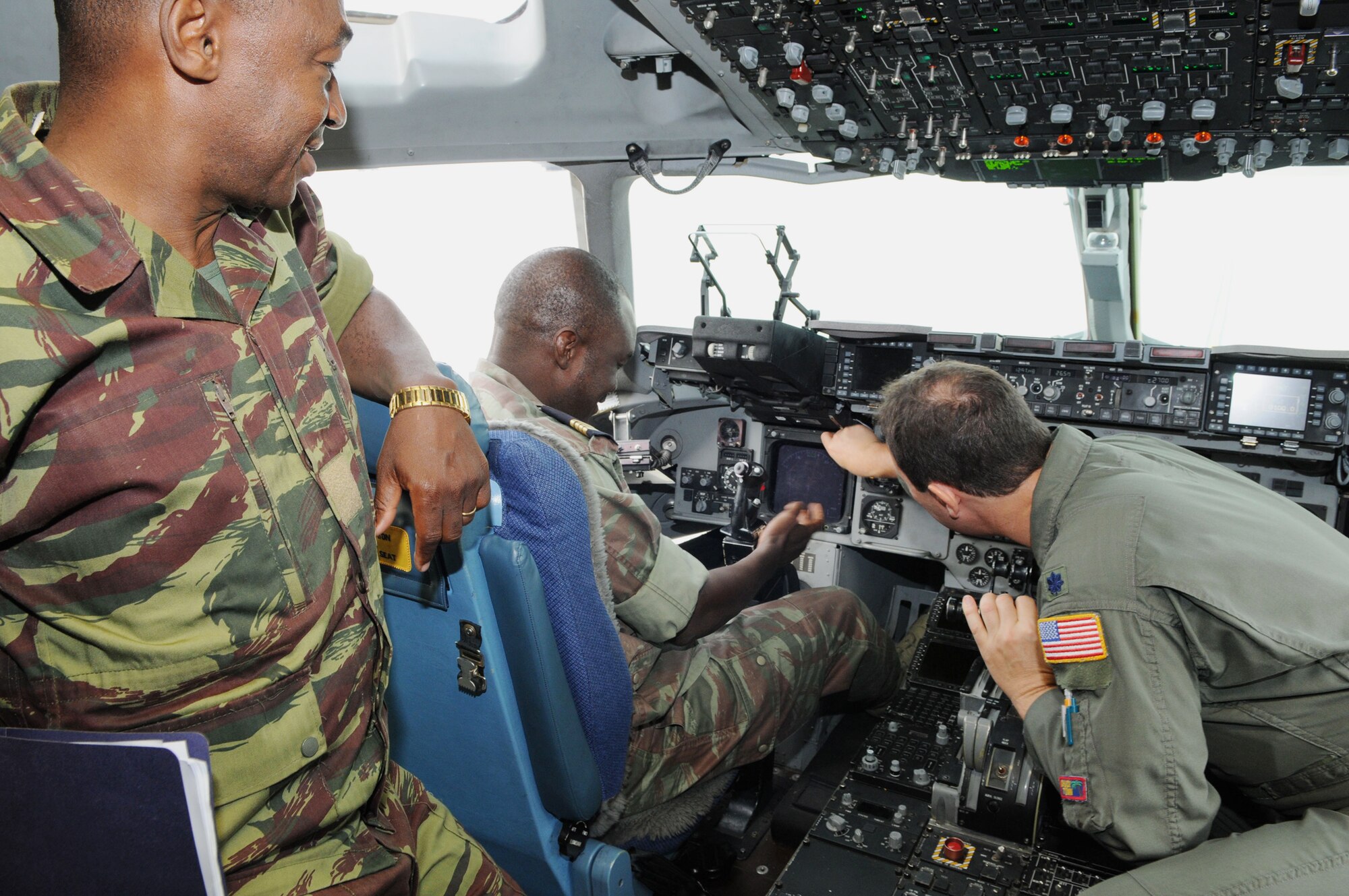Lt. Col. Douglas Slipko (right) explains cockpit controls and capabilities of the C-17 Globemaster III to Lt. Dabir Dapr Paul (left) and Maj. Souleymane Ouedraogo Aug. 14 at Ramstein Air Base, Germany. Major Ouedraogo and Lt. Paul are from Burkina Faso and part of a military exchange from the West African nation to visit U.S. bases in Germany. Colonel Slipko is assigned to the of the 17th Air Force. (U.S. Air Force photo/Tech. Sgt. Alec Lloyd) 