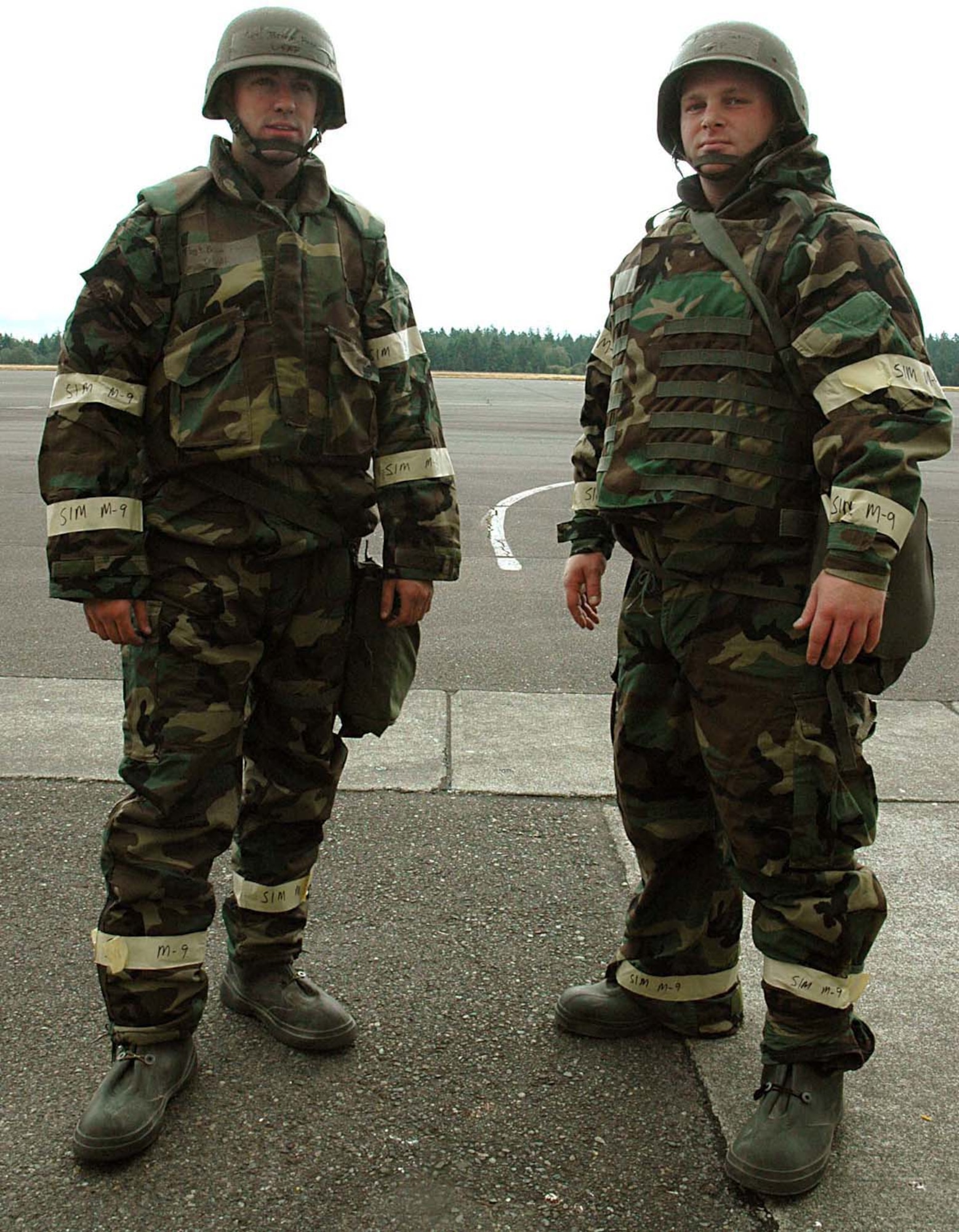 Tech. Sgt. Brian Fagan, left, and Staff Sgt. Palmer Sather model the Battle Dress Overgarment (left) and the Joint Lightweight Integrated Suit Technology overgarment as it would be worn in Mission-Oriented Protective Posture 2. In going from MOPP 1 to MOPP 2, Airmen add the wear of footwear covers. Both sergeants are with the 446th Civil Engineer Squadron emergency management flight. (U.S. Air Force photo/Senior Airman Patrick Cabellon)