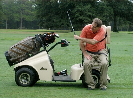 Jeff Hutcheson takes a swing at Pine Oaks Golk Course using the Solorider golf cart. Mr. Hutcheson was injured in a motorcycle accident 27 years ago and the cart has enabled him to play golf again despite being a quadraplegic.  (U. S. Air Force photo by Sue Sapp)