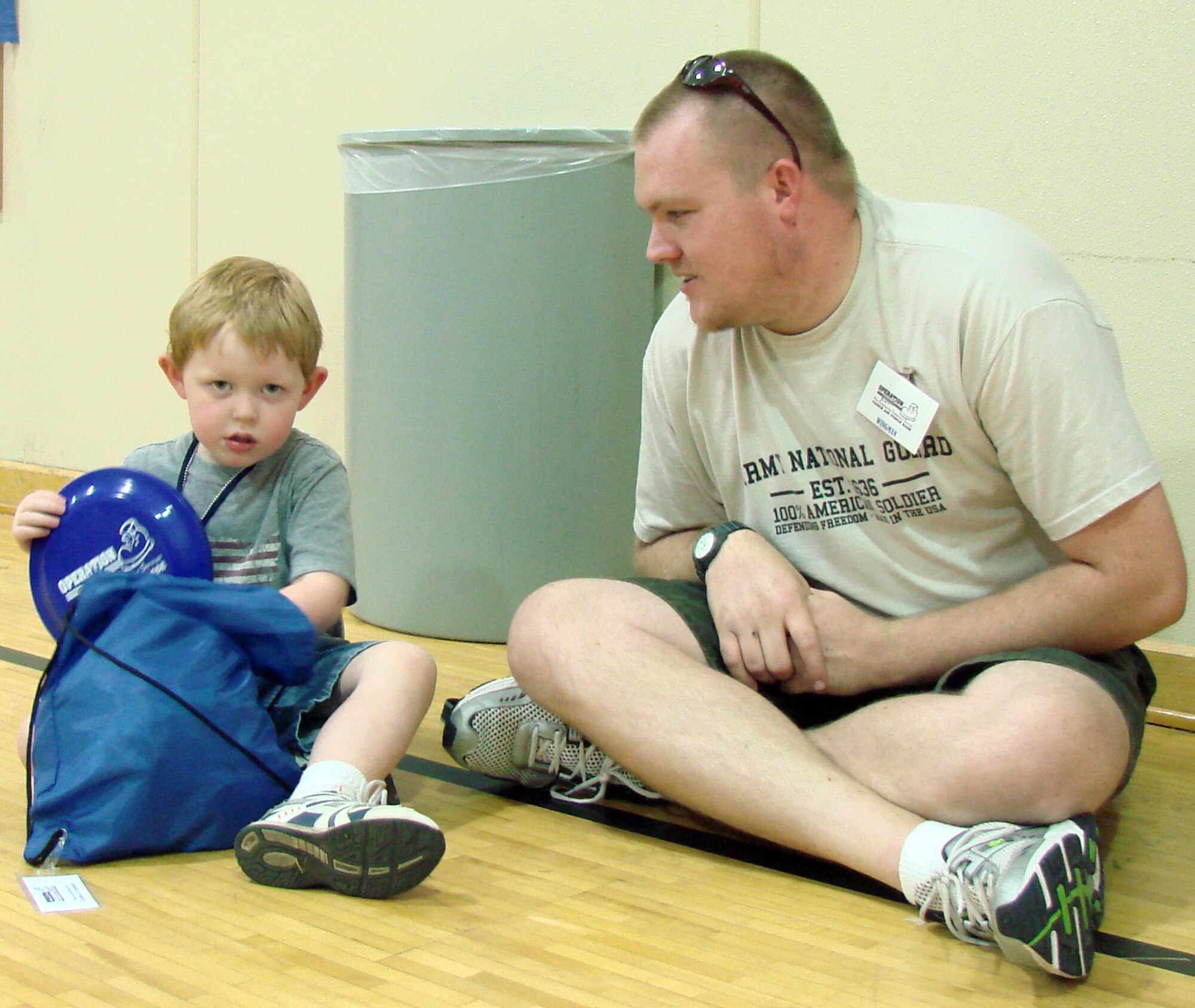 Army National Guard Prvt. Corey Conrady of the 1345th Transportation Company watches as his son, Archer Conrady, pulls a Frisbee out of the backpack he received earlier for being a participant of Operation KIDS, Aug. 6 at Vance AFB Okla. The event was a hands-on activity for children of military families to learn about their parents’ deployment process. (U.S. Air Force photo/ 1st Lt. Agneta Murnan)