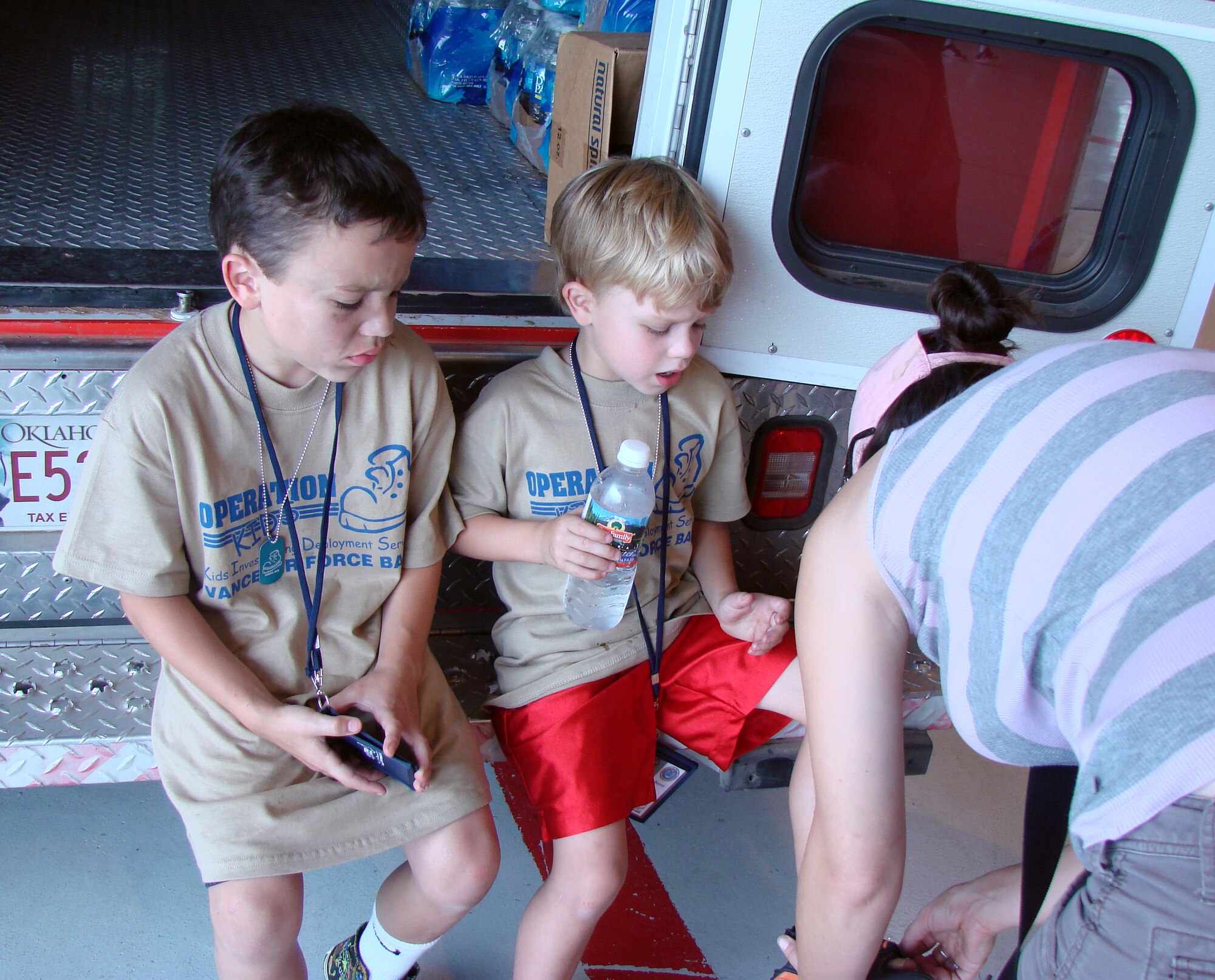 Sitting on the back of the Red Cross ambulance, Caleb Smith gets a band-aid on his foot, while Matthew Miller watches. Both boys were at Camp Liberty in Hangar 170, the “deployment” site for the Operation KIDS event, Aug. 6 at Vance AFB, Okla. The event was a hands-on activity for children of military families to learn about their parents’ deployment process. (U.S. Air Force photo/ Danielle Lutes)