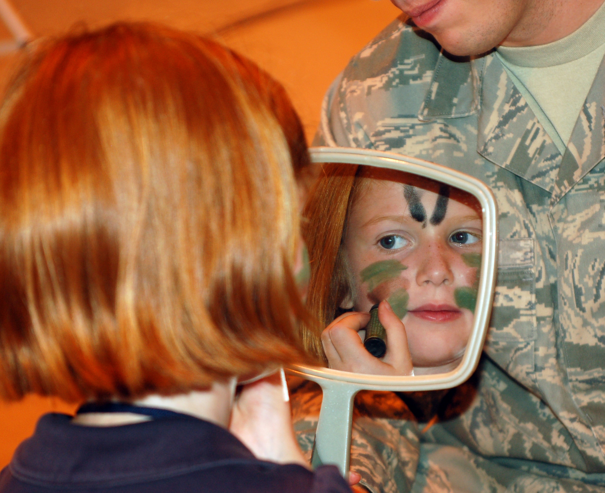Vanessa Pendley carefully applies camouflage face paint in the mirror at Camp Liberty in Hangar 170, the “deployment” site for the Operation KIDS event, Aug. 6 at Vance AFB, Okla. The event was a hands-on activity for children of military families to learn about their parents’ deployment process. (U.S. Air Force photo/ Lisa Hoth)
