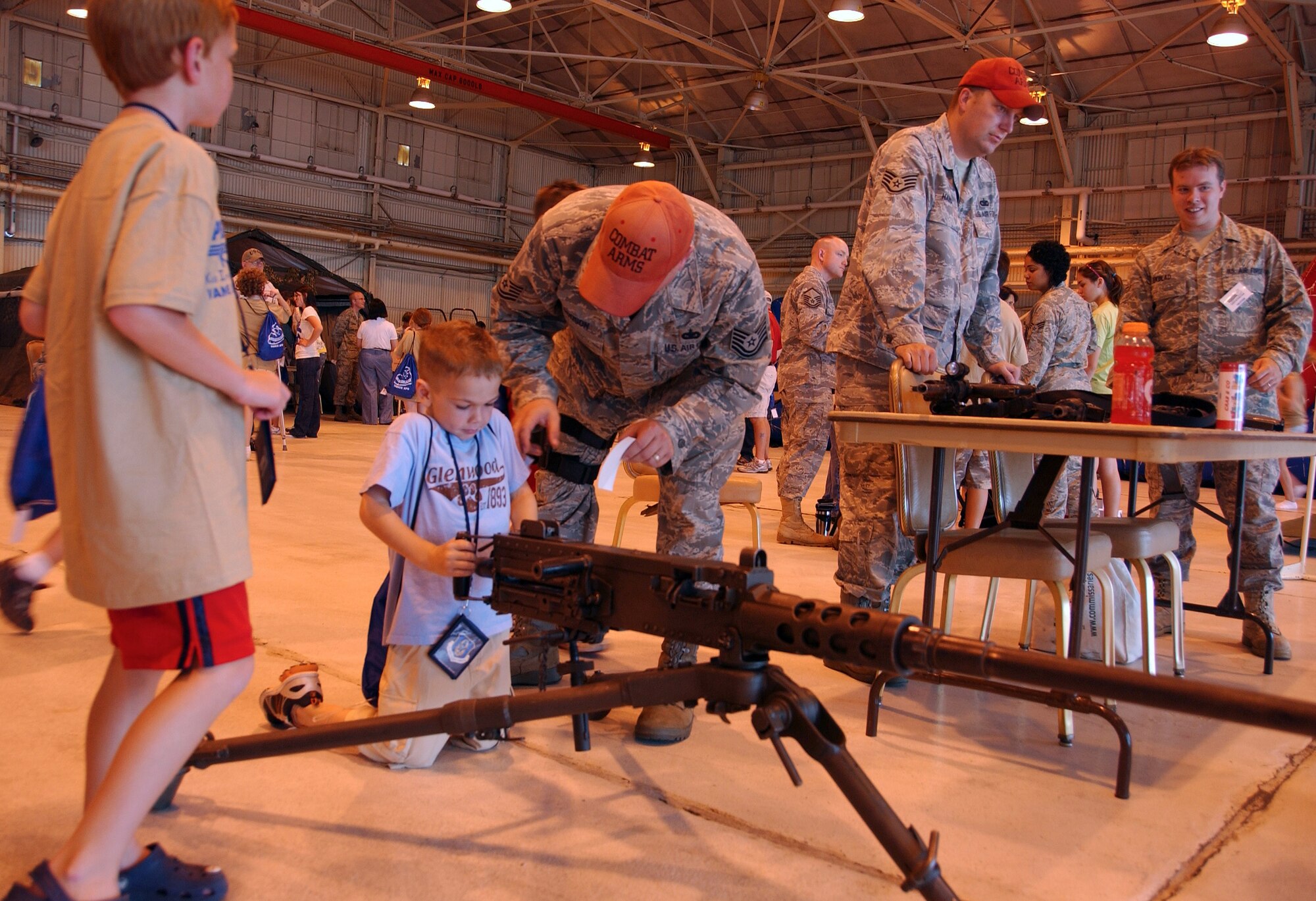 Technical Sgt. Richard Dodson, of the 71st Security Forces Squadron Combat Arms Training and Maintenance Team, explains the workings of a .50-caliber machine gun to one of the children at Camp Liberty in Hangar 170, the “deployment” site for the Operation KIDS event, Aug. 6 at Vance AFB, Okla. The event was a hands-on activity for children of military families to learn about their parents’ deployment process. (U.S. Air Force photo/ 1st Lt. Agneta Murnan)