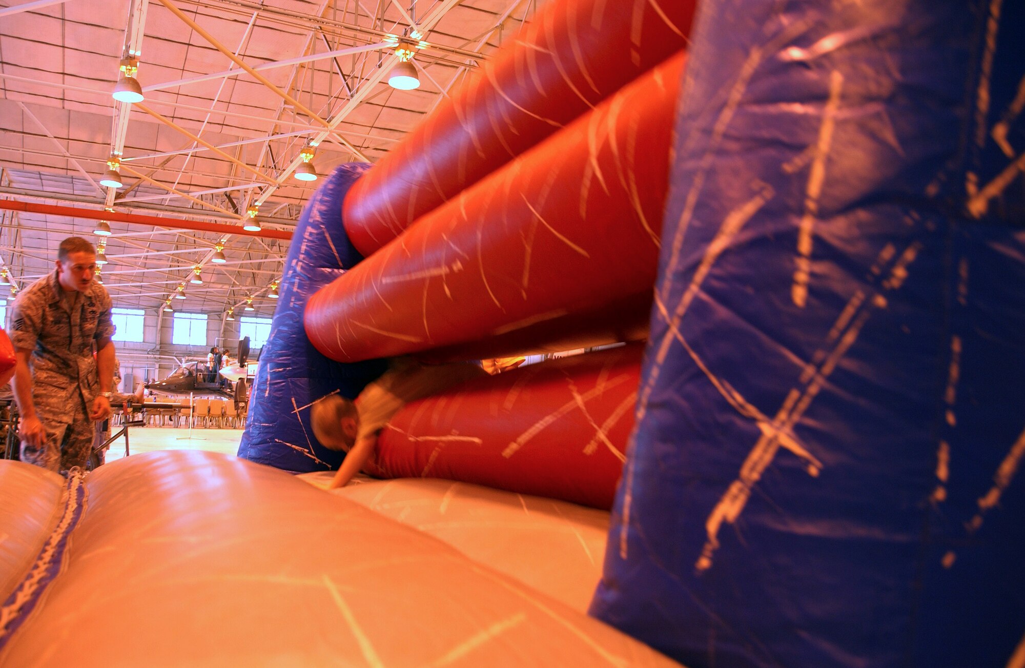 Staff Sgt. Jeremy York tries not to blink as children barrel through the inflatable obstacle course at Camp Liberty in Hangar 170, the “deployment” site for the Operation KIDS event, Aug. 6 at Vance AFB, Okla. The event was a hands-on activity for children of military families to learn about their parents’ deployment process. (U.S. Air Force photo/ 1st Lt. Agneta Murnan)