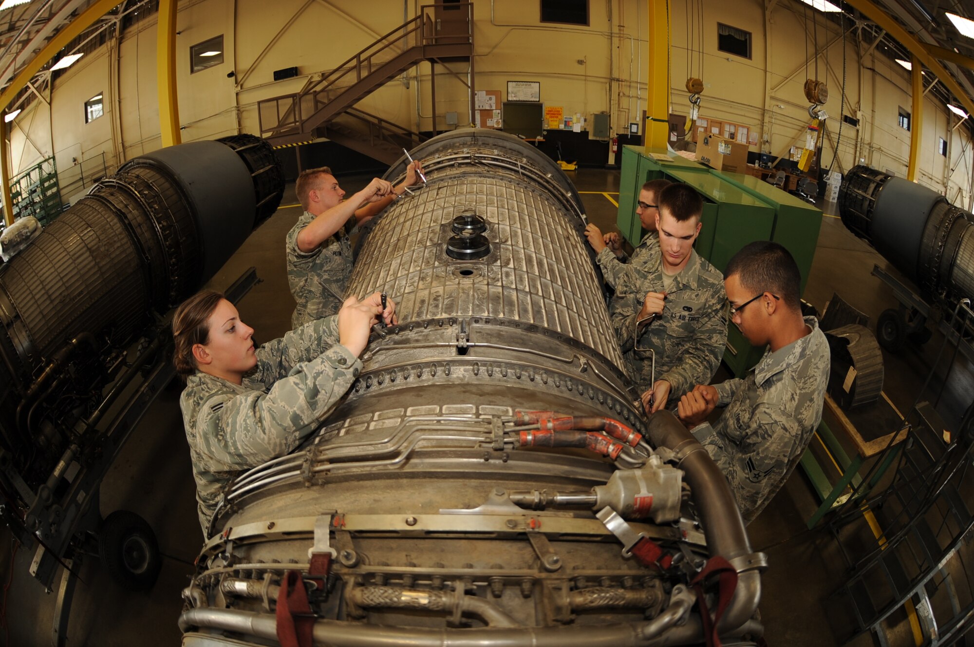 (Left to right) Airman 1st Class Stacie Powers, Jason Pettine, Jon Bettenhausen, Justin Hildreth and Khayan Martinez, 28th Maintenance Squadron aerospace propulsion apprentices, remove bolts as a team from a fan duct on a B-1B Lancer engine here, August 13.  The Airmen remove the fan duct to access blades in need of repair. (U.S. Air Force photo/Airman 1st Class Anthony Sanchelli)