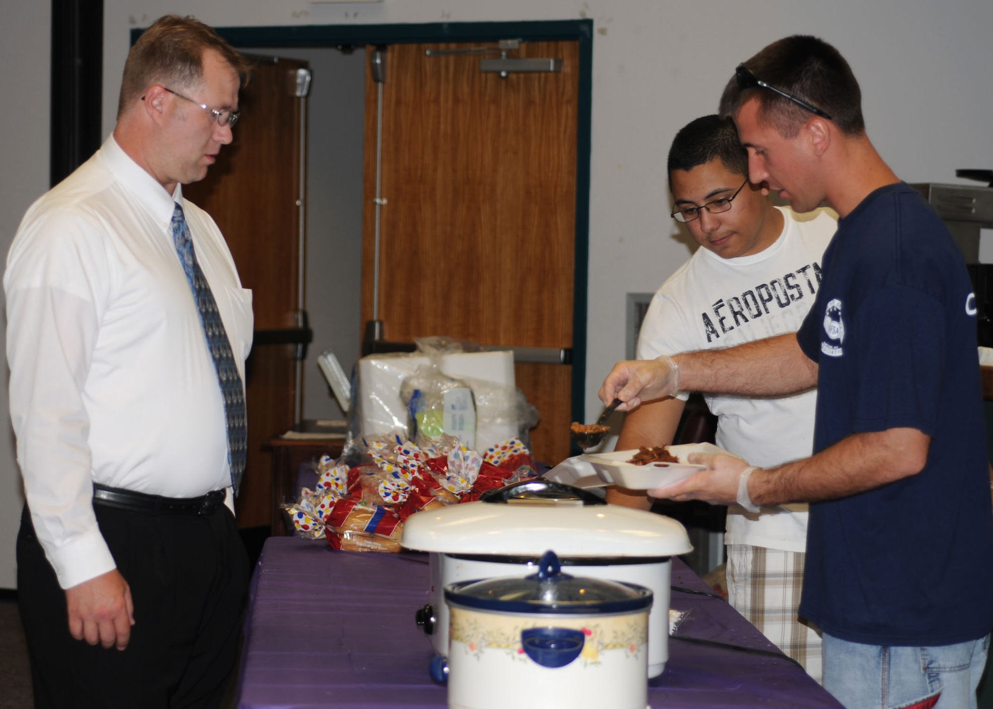 ALTUS AIR FORCE BASE, Okla. – Airman 1st Class Marcos Sanchez, 97th Force Support Squadron, and Staff Sgt. Travis Sidel, 97th Training Squadron, serve food to Special Agent Richard Hughes during an Air Force Sergeant’s Association fundraiser at the Freedom Community Center Aug. 17. Money raised will go to various functions such as funding ceremonies, graduations, donations to charity and scholarships. (U.S. Air Force photo/Airman 1st Class Tiffany M. Deuel)