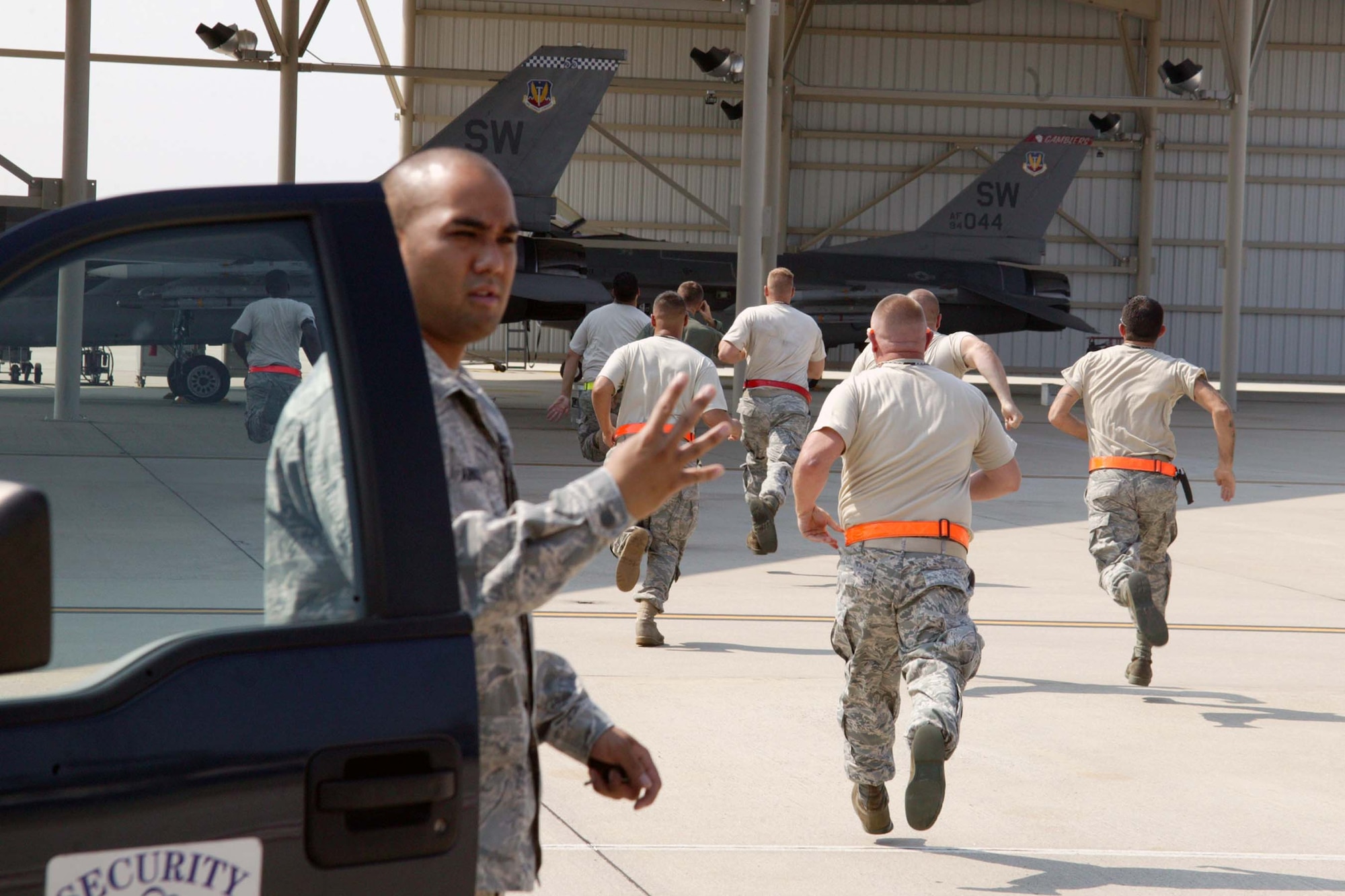 SHAW AIR FORCE BASE, S.C. -- The alert maintenance crew dash to their F-16s to prepare them for takeoff on a quick-reaction mission exercise Aug. 11, while Airman Basic  Julian Arnold, 20th Security Forces Squadron, checks badges to make sure everyone has proper access. The exercise, with cooperation from the Civil Air Patrol, provides interception training for Shaw's alert force for real-world situations. (U.S. Air Force photo/Staff Sgt. John Gordinier)