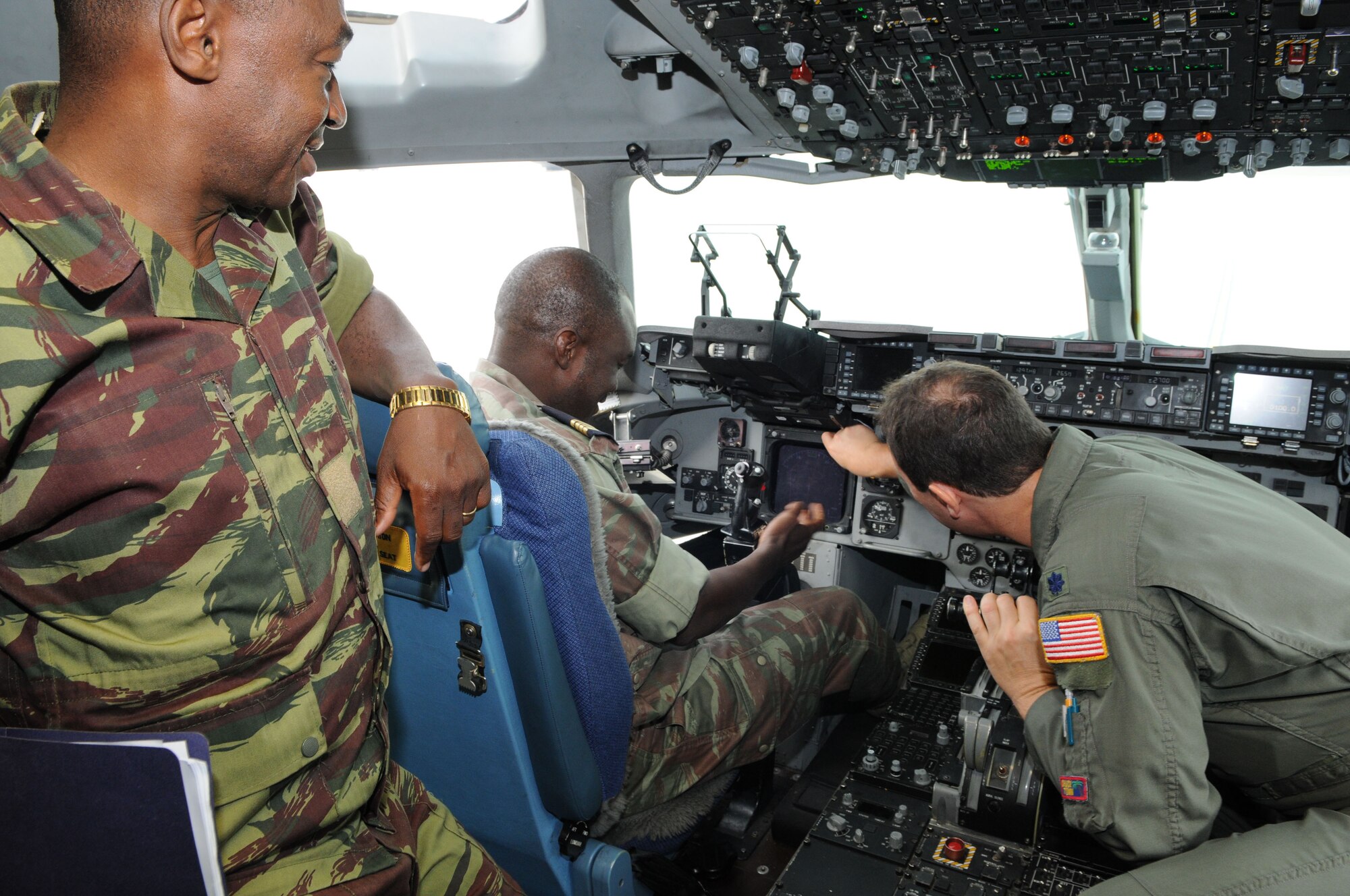 Lt. Col. Douglas Slipko of the 17th Air Force (U.S. Air Forces Africa),  right, explains cockpit controls and capabilities of the C-17 to Lt. Dabir? Dapr? Paul, left, and Maj. Souleymane Ouedraogo at Ramstein Air Base.  Major Ouedraogo and Lt. Paul are from Burkina Faso and part of the first-ever military exchange from the West African nation to visit U.S. bases in Germany. (USAF photo by Tech. Sgt. Alec Lloyd)