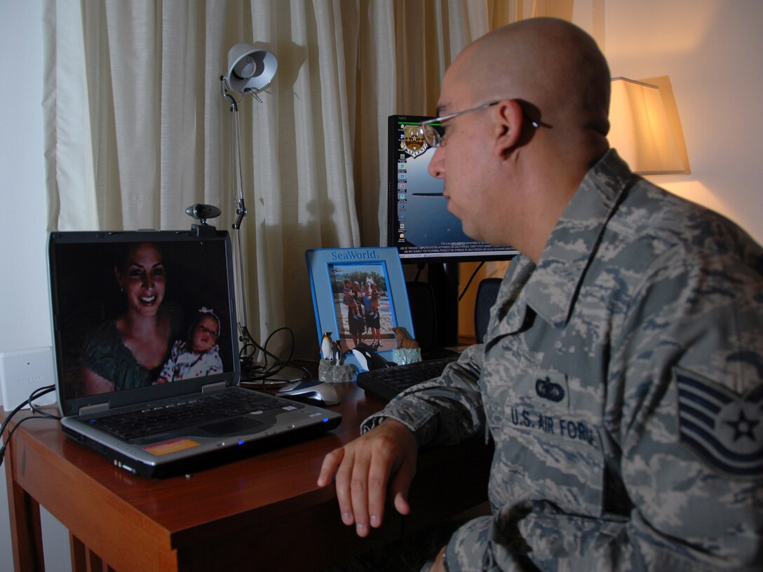 Tech. Sgt. Rafael Garcia, 379th Expeditionary Mission Support Group knowledge operations management  NCOIC, talks via Webcam with his wife, Monica, and daughter, Carmella Fe, here, Aug. 18. Sergeant Garcia, a native of Chicago, recently experienced the birth of his daughter via Webcam from a deployed location in Southwest Asia. He is deployed from Ramstein Air Base, Germany in support of Operations Iraqi and Enduring Freedom.  (U.S. Air Force Photo/Tech. Sgt. Jason W. Edwards)