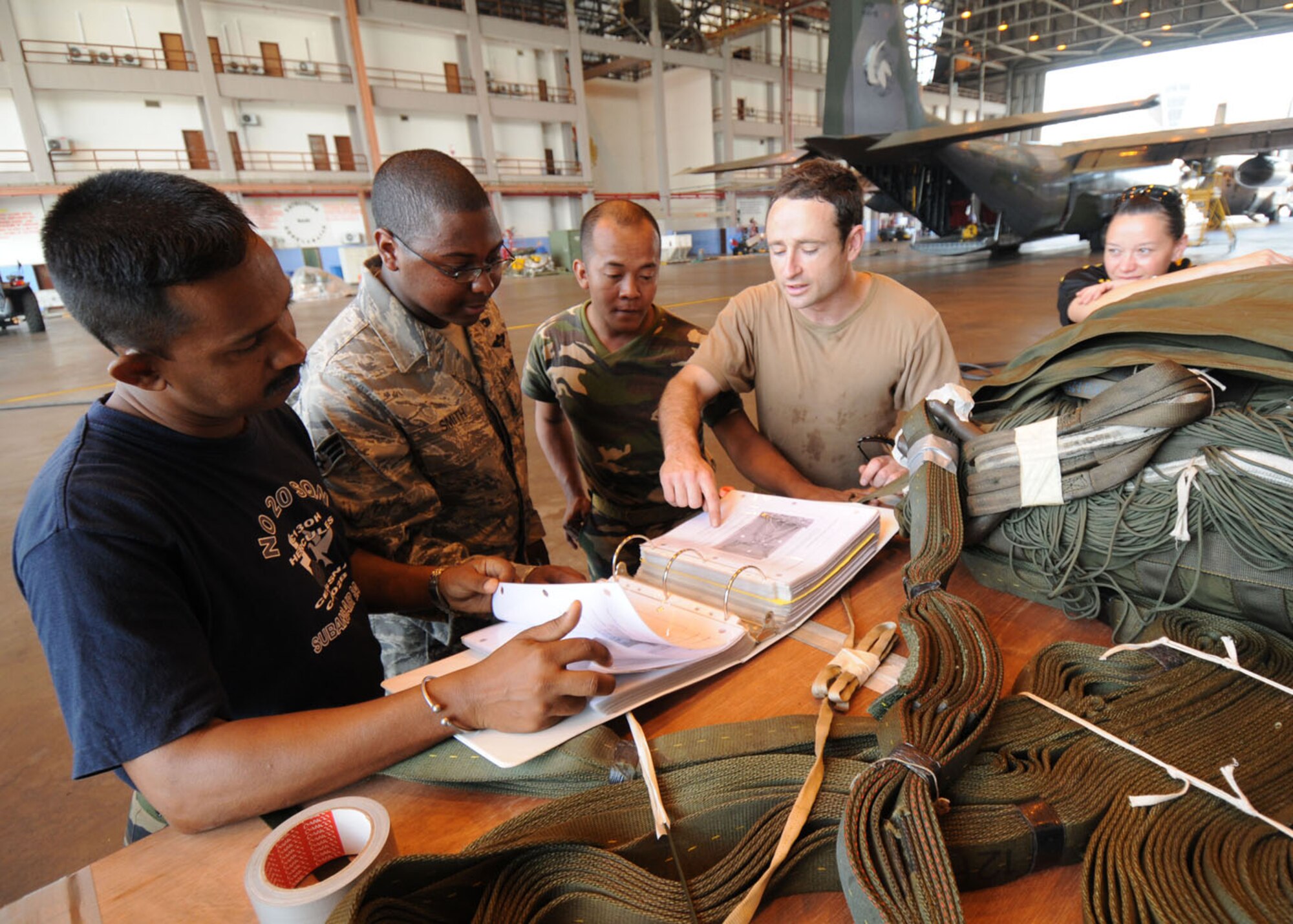 SUBANG ROYAL MALAYSIAN AIR FORCE BASE, Malaysia -- (Second from left) Senior Airman Warren Smith, 374th Logistics Readiness Squadron combat mobility flight technician from Yokota Air Base, Japan, views technical orders on how to properly rig for air drops with personnel from Malaysia, Australia and New Zealand air forces Aug. 19 during the 2009 Pacific Airlift Rally here. The PAR is a bi-annual exercise involving Pacific Rim nations which enhances military airlift interoperability with a focus in humanitarian assistance and disaster relief operations. The exercise consists of a tabletop exercise and a field-training exercise involving three C-130 aircraft from the 374th Airlift Wing at Yokota and one C-130 each from the Royal Malaysian Air Force, Royal Australian Air Force, Republic of Singapore Air Force and Royal New Zealand Air Force. (U.S. Air Force photo/Staff Sgt. Veronica Pierce)