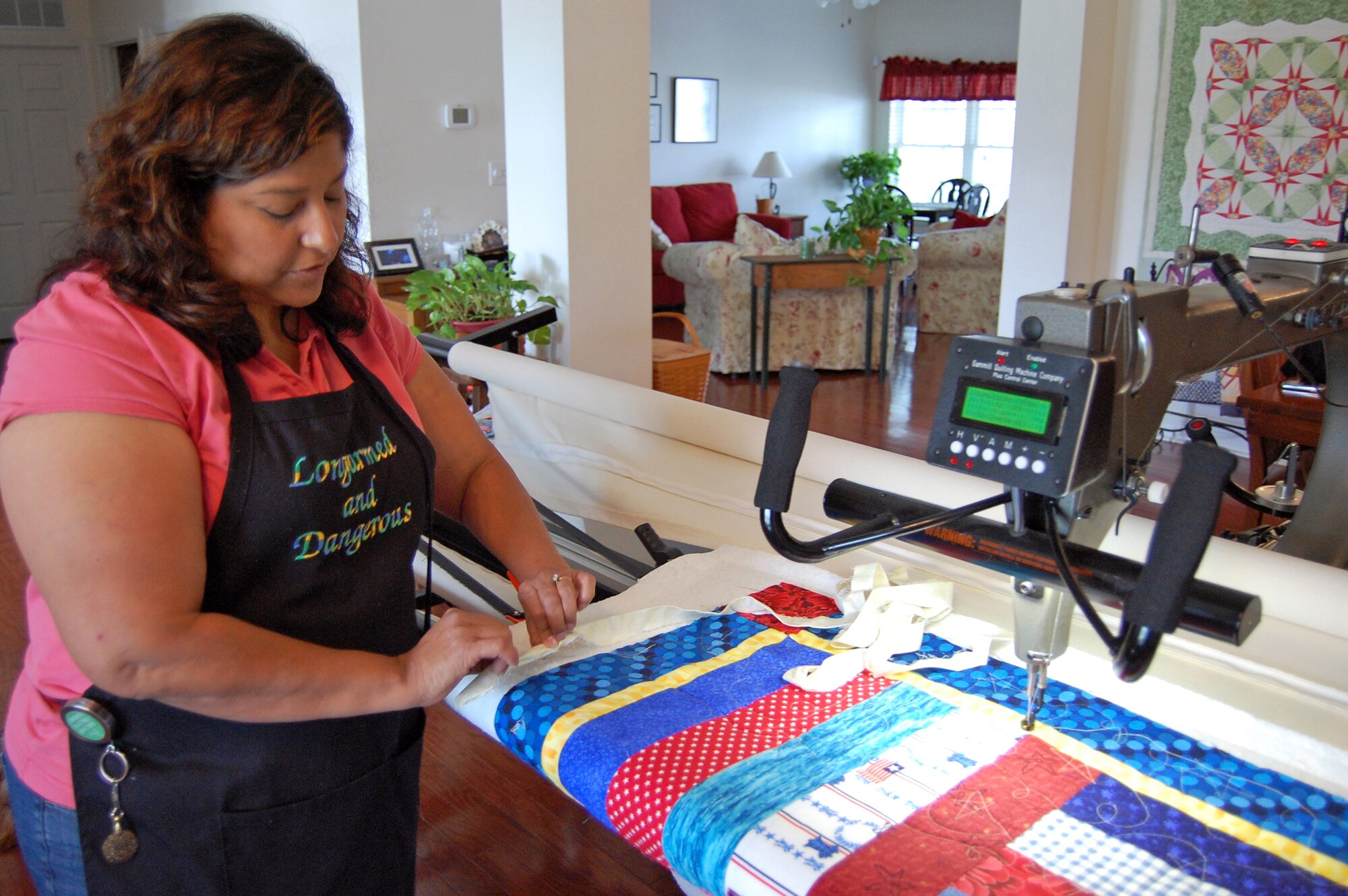 Irene Hafer checks the edge on a Quilts of Valor quilt June 24 in her home studio in Dover, Del. Her apron reads "Longarmed and Dangerous," a reference to the longarm machine she uses to stitch together the three layers of a quilt. (U.S. Air Force photo/Tech. Sgt. Benjamin Matwey)