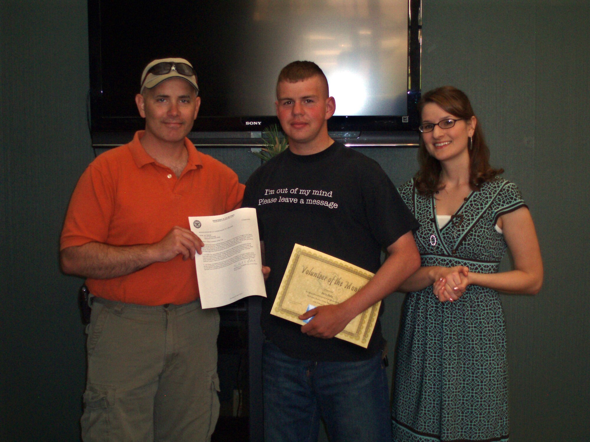 Chaplain (Capt.) Thomas Woodruff, 341st Missile Wing chaplain, along with Julie Wiseman, Detour coordinator, recognize Airman 1st Class Justin Daley, 741st Missile Security forces Squadron, for his more than 400 hours of volunteer service to the Detour during an informal ceremony Aug. 9. Airman Daley was named Volunteer of the Month three times over the past year which also earned him the Volunteer of the Year distinction. (U.S. Air Force courtesy photo)   