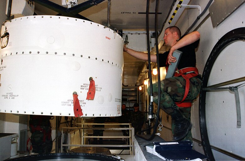 From inside a payload transporter van during the first booster replacement at Malmstrom April 16, 2001, Airman 1st Class  Roger Ridley, 341st Maintenance Squadron, lowers a missile guidance set onto the booster in launch facility Hotel-02 below. (U.S. Air Force photo/John Turner)