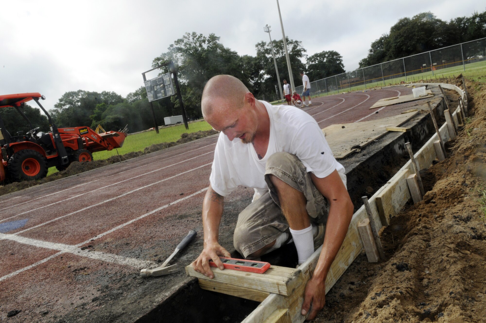 Jason Davis, Competition Athletic Fields, works on completing the outside curbing on the outdoor track at the Fitness center. It's just one of dozens of projects the 78th Force Support Squadron is working to improve quality of life for its customers.  (U. S. Air Force photo by Sue Sapp)   