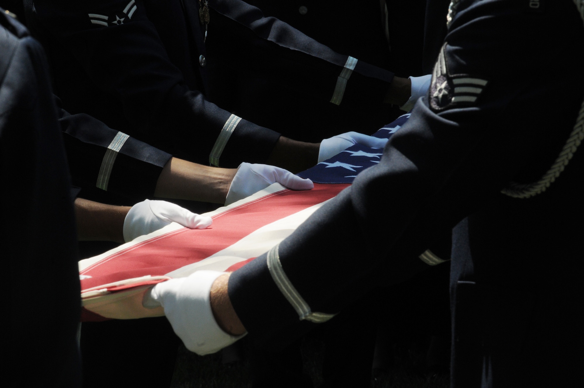 A United States Air Force Honor Guard body bearer team folds the U.S. flag during a full-honors funeral ceremony at Arlington National Cemetery. Honor Guard body bearers train constantly to maintain the precision they are known for. Their standards of flawlessness are set out of necessity to honor fallen Airmen. (U.S. Air Force photo/Senior Airman Sean Adams)