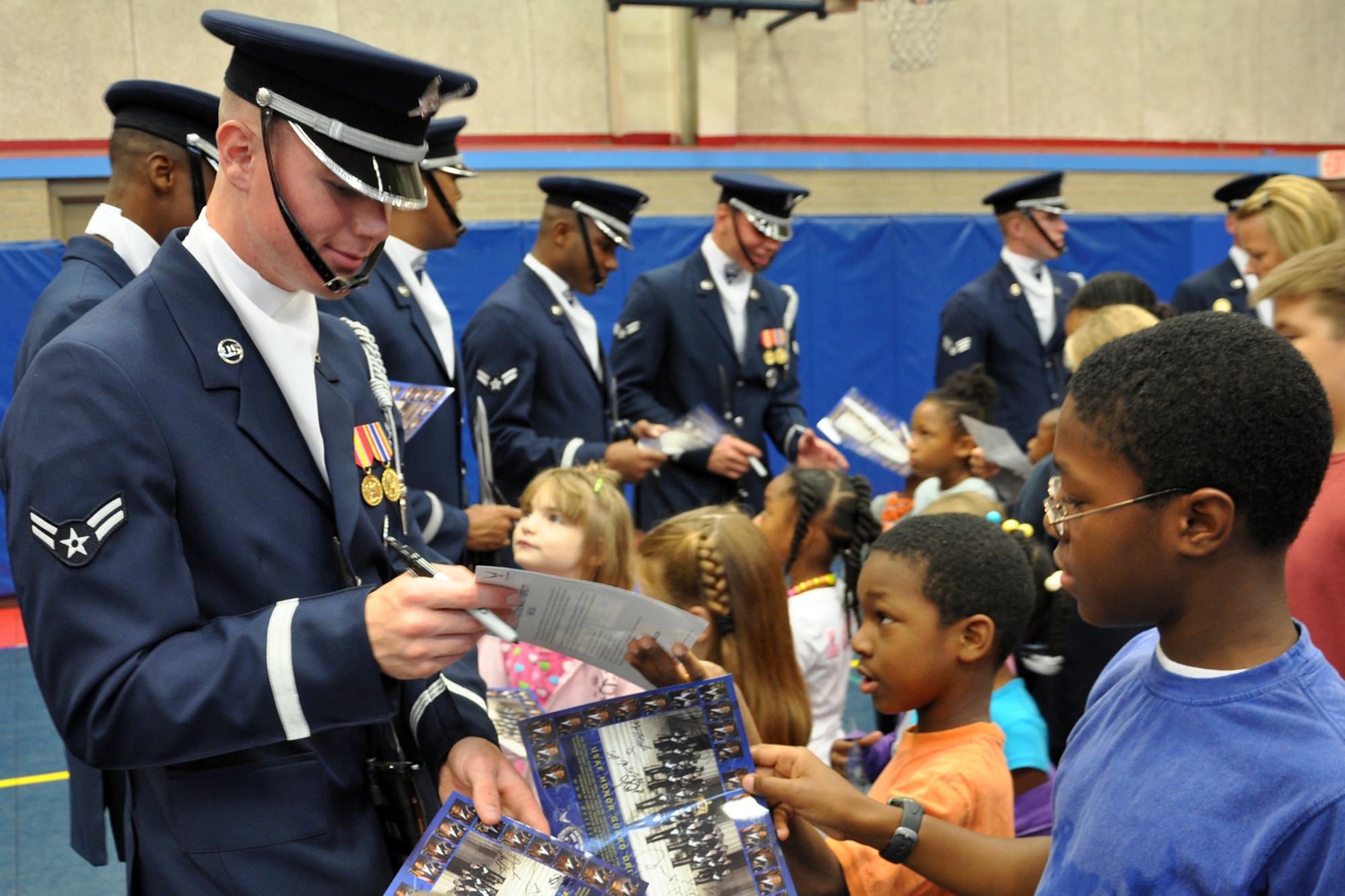 EGLIN AIR FORCE BASE, Fla. – The USAF Honor Guard Drill Team signs autographs for new fans at the Child Development Center here, Aug. 17. The 16-person team performed professionally choreographed sequence of weapon maneuvers, precise tosses, complex weapon exchanges and a walk through the gauntlet of spinning, 11-pound M-1 Garande rifles with fixed bayonets. The Drill Team is the traveling component of the USAF Honor Guard that promotes Air Force awareness among military and civilian audiences through their routines. (U.S. Air Force photo/ Airman Anthony Jennings)