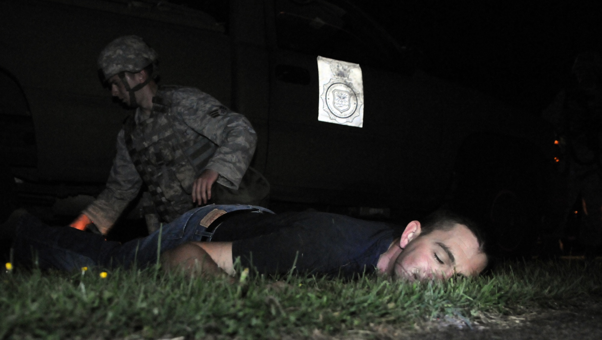 RAF MILDENHALL, England – A 100th Security Forces Squadron Airman searches the simulated dead body of an Opposition Forces team attacker during an exercise Aug 17.  OPFOR members infiltrated the simulated deployed base and caused as much disruption as they could before they were stopped by security.  (U.S. Air Force photo by Staff Sgt. Austin M. May)