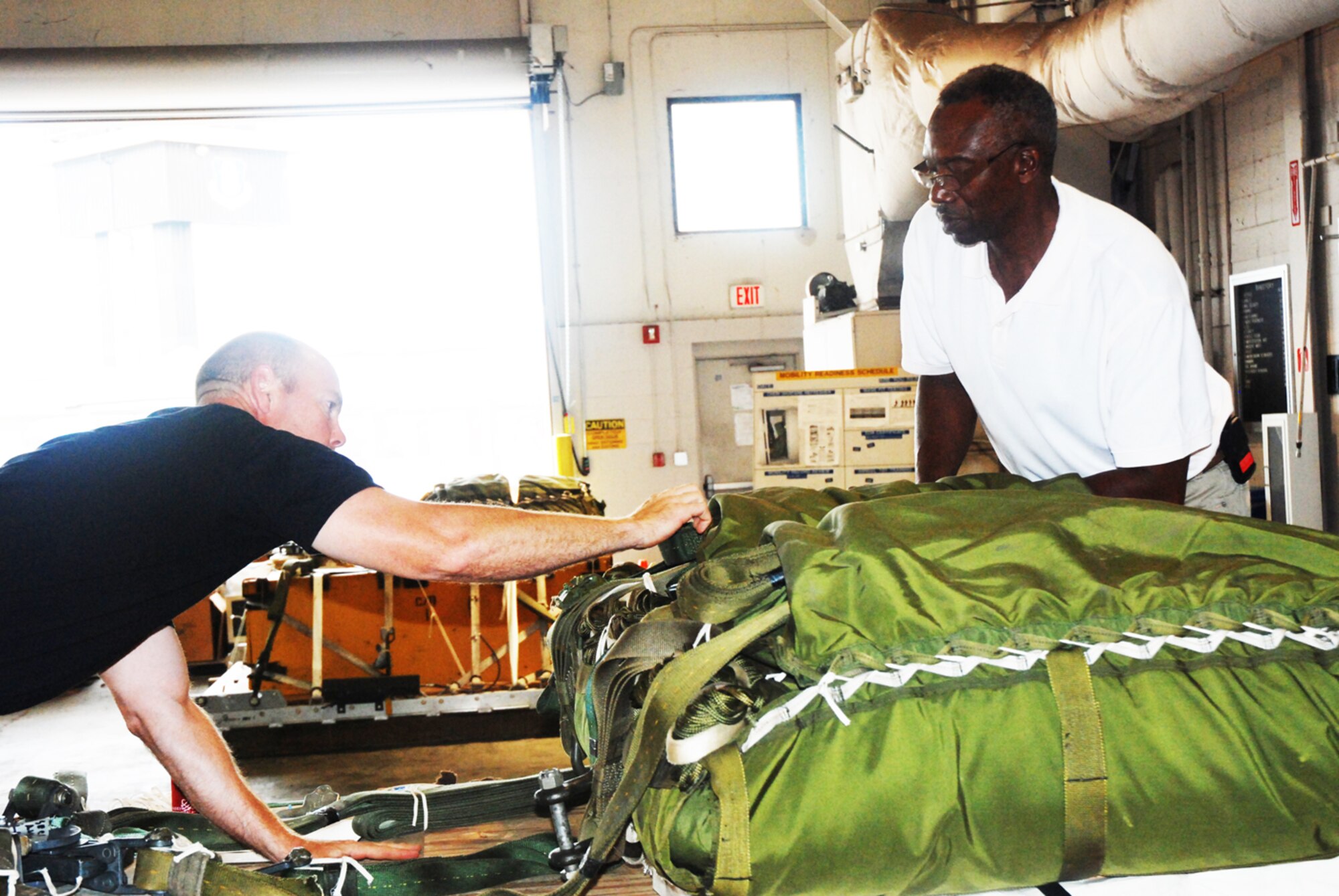 Gerald McKnight and Staff Sgt. Dallas Criswell of the 94th Aerial Delivery Flight build a "heavy," which is a load of materials that will be dropped out of a C-130 aircraft. (U.S. Air Force photo/Kennith Green)