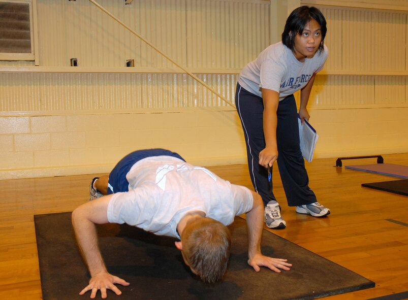 Joyce Jankielsztajn, Kadena Health and Wellness Center fitness testing specialist, explains the proper way to perform push-ups to Airmen preparing to take their Performance Fitness Test Aug. 14. All fitness testing at Kadena is now conducted by specialists at the HAWC to ensure standardization as part of a mandate by Gen. Carrol Chandler, Pacific Air Forces commander.     
(U.S. Air Force photo/Staff Sgt. Christopher A. Marasky)