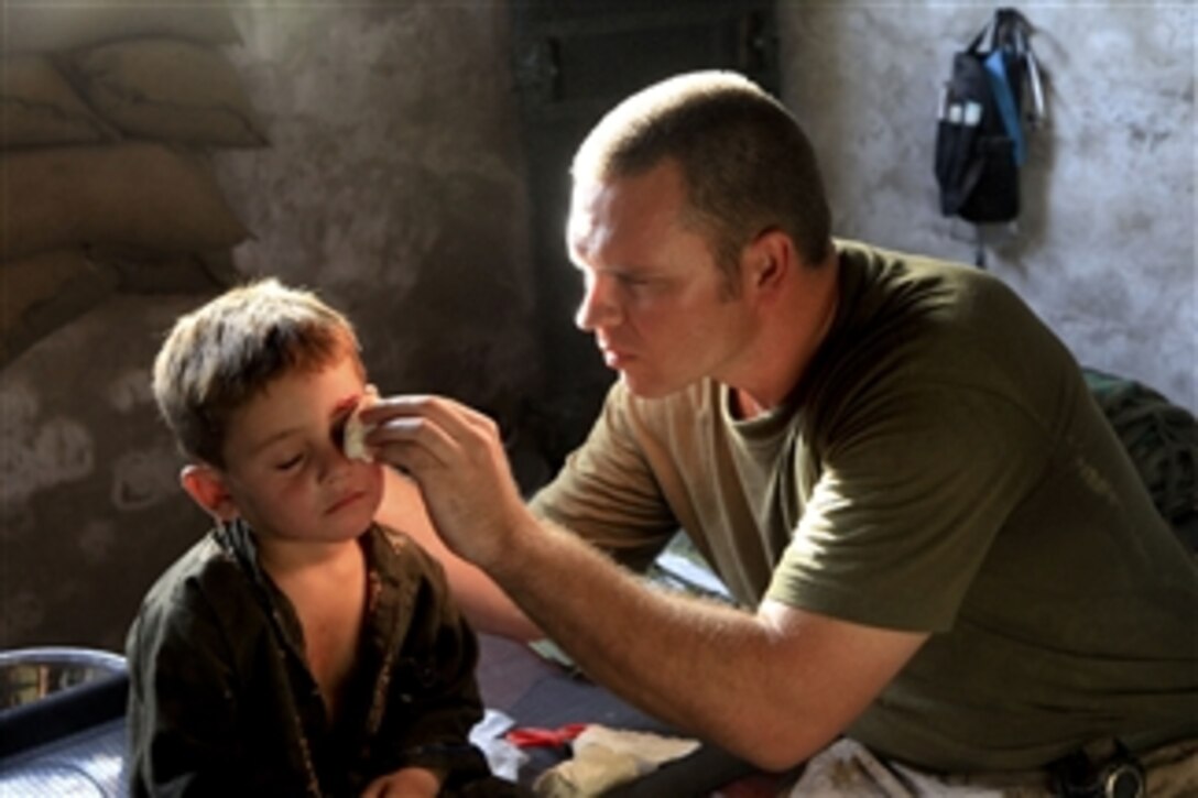 An Afghan boy is treated by a U.S. Navy hospital corpsman with Headquarters Company, 1st Battalion, 5th Marine Regiment at Patrol Base Jaker in the Nawa district of Helmand province, Afghanistan, on Aug. 11, 2009.  The boy's father brought him to the base saying that his son had fallen into a nearby canal.  The Marines are deployed with Regimental Combat Team 3 to conduct counter insurgency operations in partnership with Afghan National Security Forces in southern Afghanistan.  