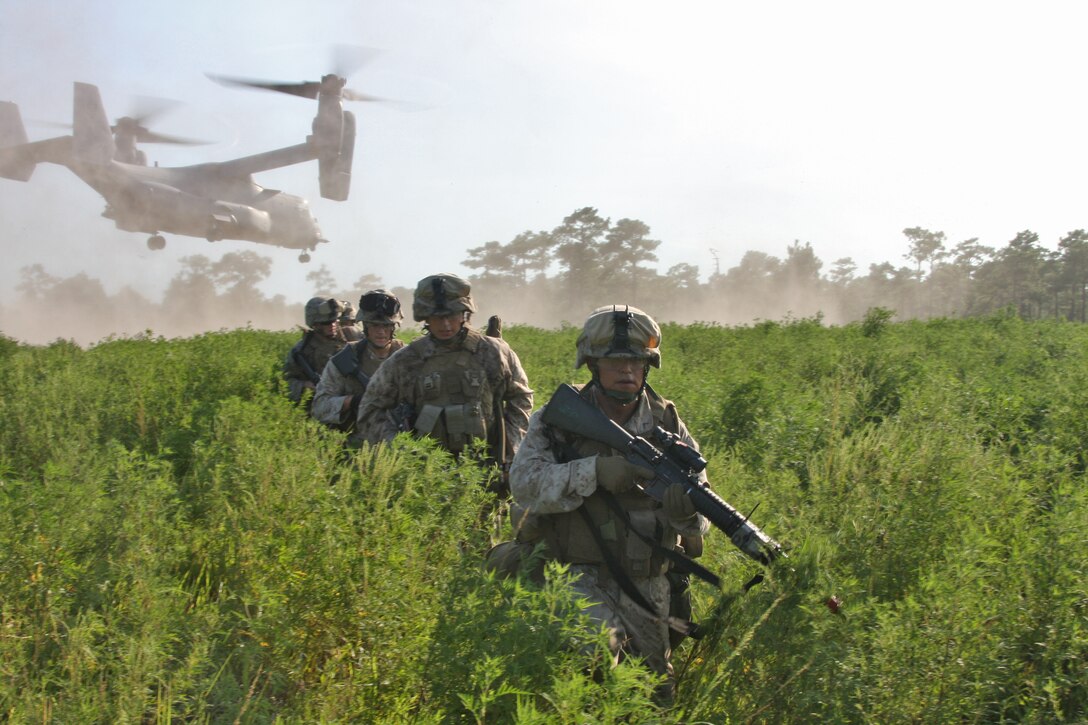 Pfc. Tony J. Desselle, rifleman, 2nd platoon, Charlie Company, Battalion Landing Team 1st Battalion, 9th Marine Regiment, 24th Marine Expeditionary Unit, leads his Marines to a collection area as a MV-22 Osprey, from Marine Medium Tilt Rotor Squadron -162, 24th MEU, takes flight after transporting Marines to a raid training facility at Camp Lejeune, N.C. Aug. 19, during the Heliborne Company Raid Course.  Charlie Company trained with Special Operations Training Group to become the 24th MEU’s helo raid force for its upcoming deployment.  (U.S. Marine Corps photo by Cpl. Alex C. Guerra)