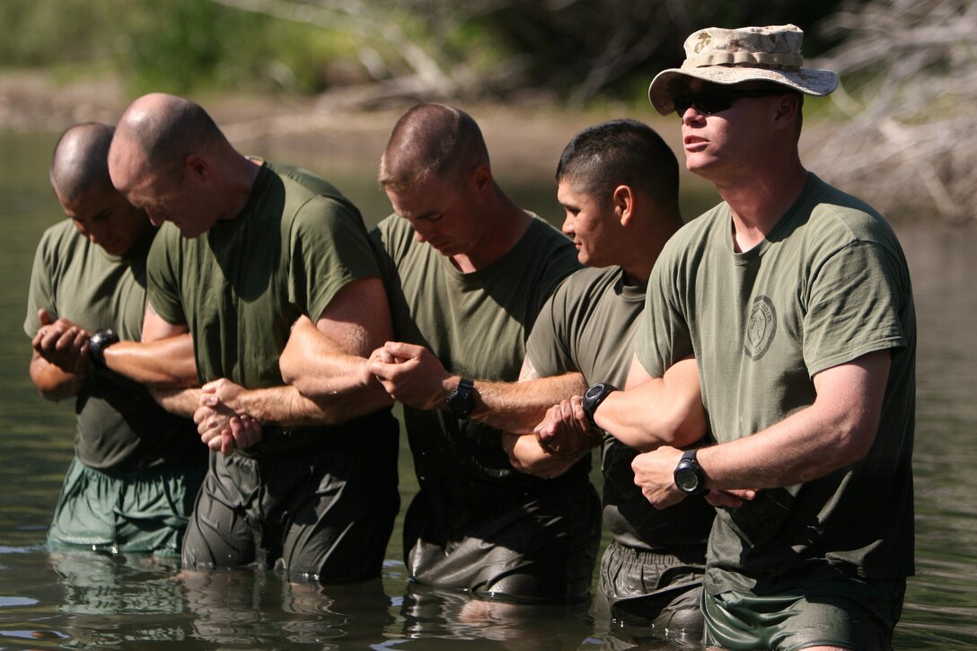 Staff Sgt. Jeremy Miller [right], an instructor with the Unit Training Group, demonstrates to Marines and sailors of 3rd Battalion, 7th Marine Regiment, based out of Marine Corps Air Ground Combat Center Twentynine Palms, Calif.,  a technique used to cross small rivers and streams during a training exercise at the Leavitt Training Area here Aug. 20. Training to become a UTG instructor is a long process, taking nearly three years to reach the highest mountain warfare instructor classification, MWI III.