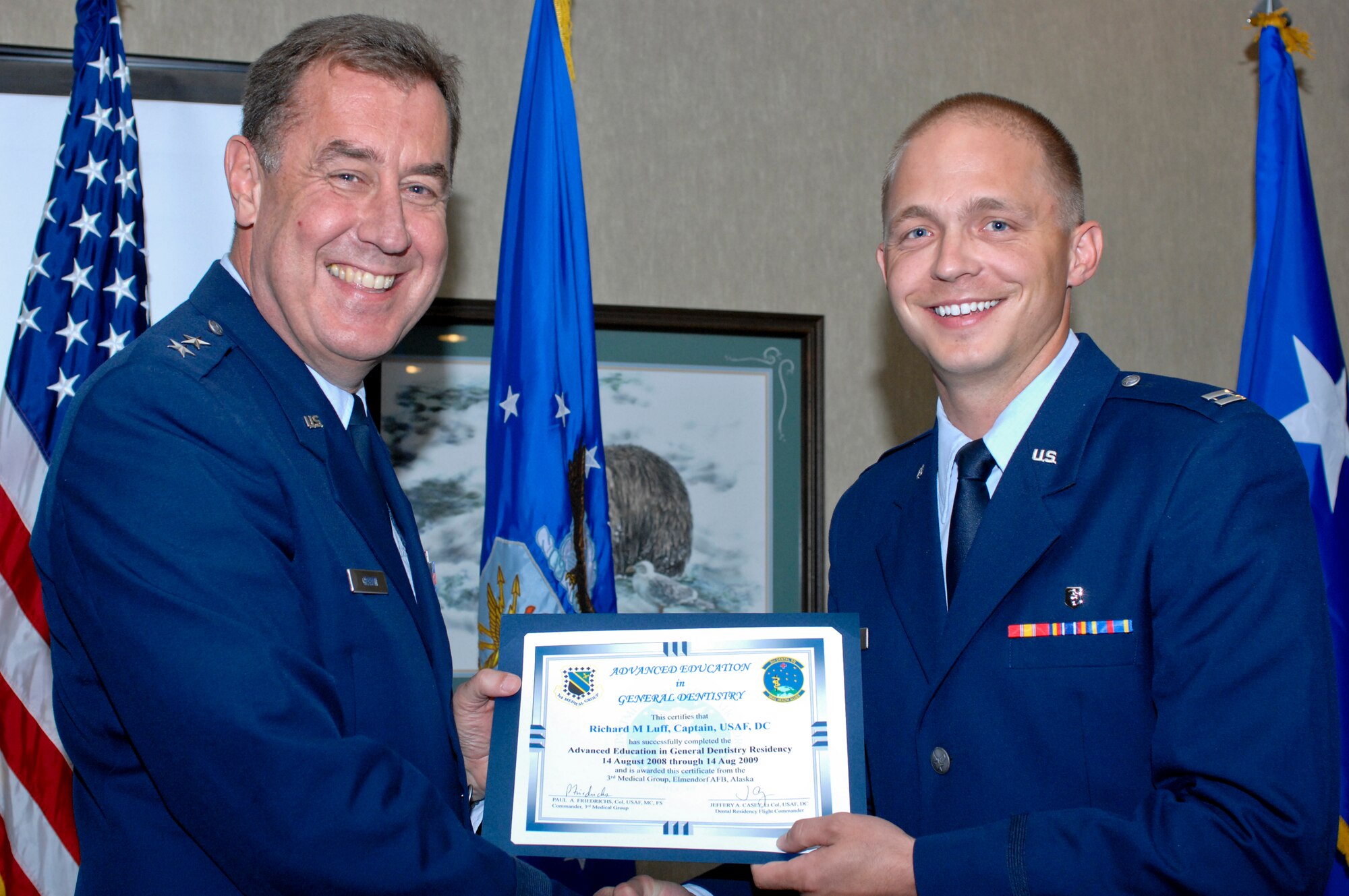 ELMENDORF AIR FORCE BASE, Alaska -- Maj. Gen. Gar Graham presents a residency graduation certificate to Capt. Richard Luff during the ceremony at the Susitna Club Aug. 14. Luff was one of three members of the 3rd Dental Squadron to receive their certificates from the Advanced Education in General Dentistry here. The year-long program gives additional training to the new dentists so they can provide dental care without supervision. Graham is the Air Force assistant surgeon general for dental services. (U.S. Air Force photo/Airman Jack Sanders)