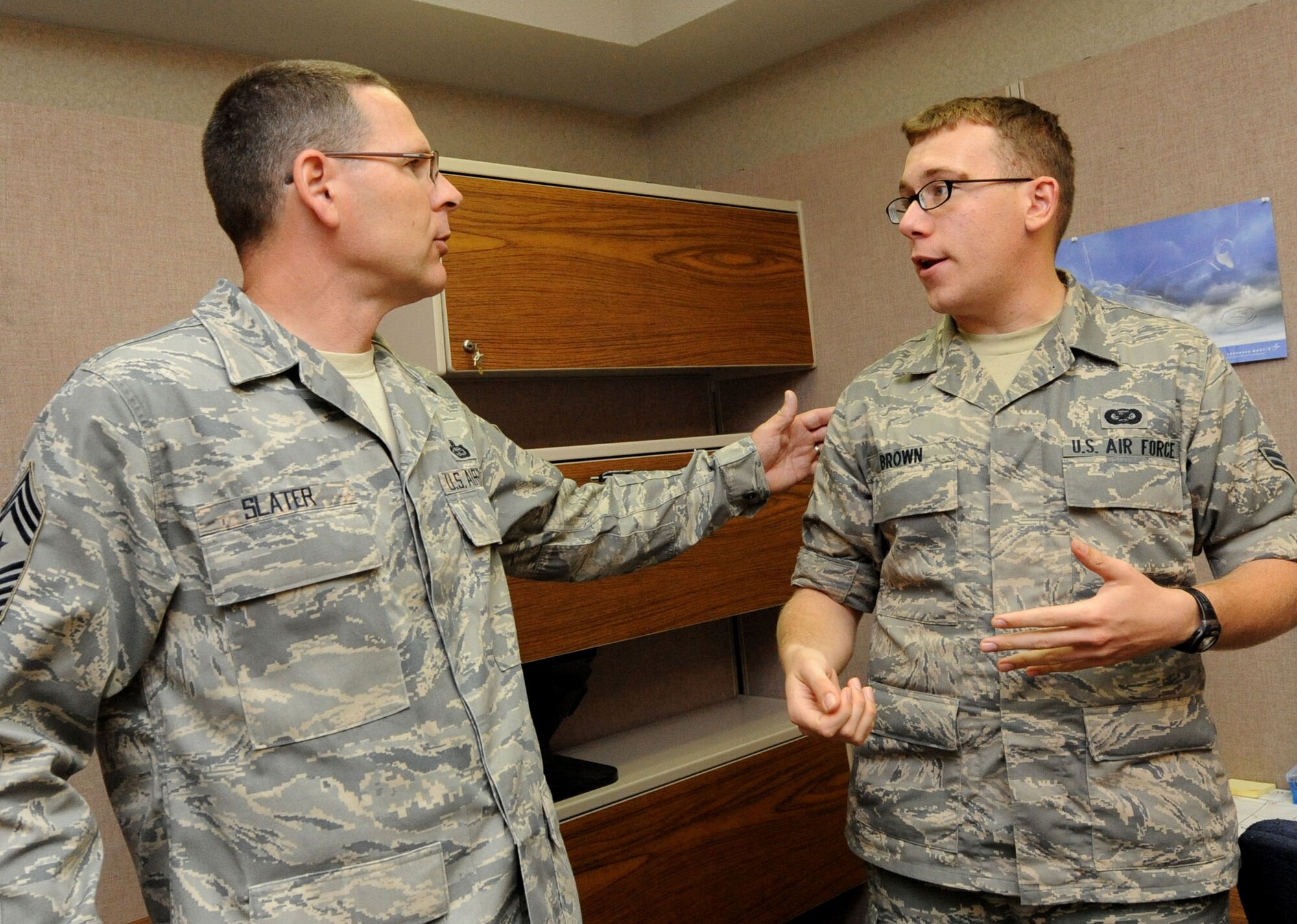 LANGLEY AIR FORCE BASE, Va. -- Chief Master Sgt. Kevin Slater, 1st Fighter Wing command chief, discusses story ideas with Airman 1st Class Jason Brown, 1st FW Public Affairs journalist, during his tour here Aug. 20.  Chief Slater learned basic tasks performed by photographers, broadcasters, and journalists during his tour of PA. (U.S. Air Force photo/Airman Rebecca Montez)